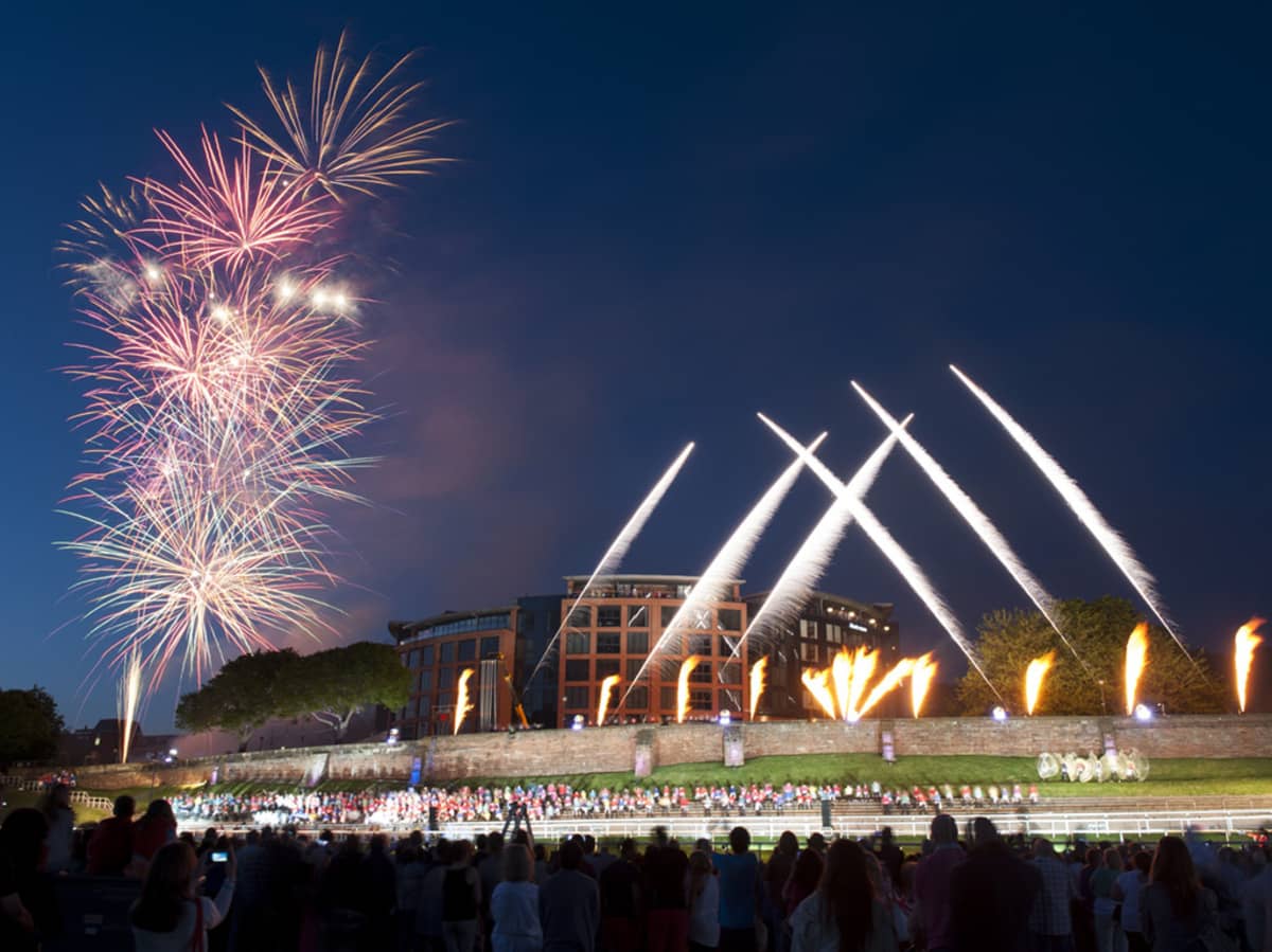 Fireworks and pyrotechnics display over Chester racecourse at night with crowds watching