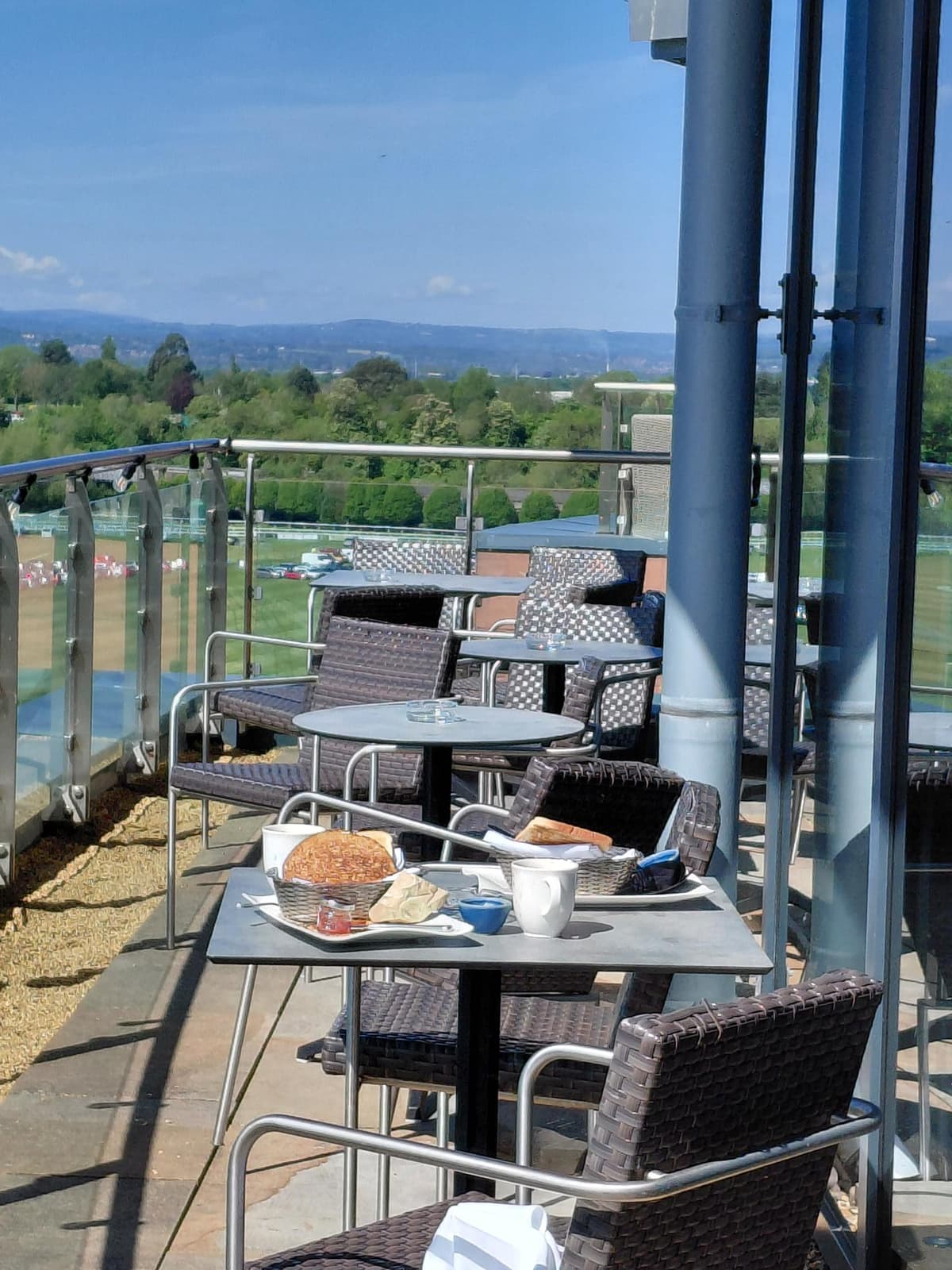 Elevated terrace at Abode Chester with rattan chairs, bread and tea overlooking the racecourse.