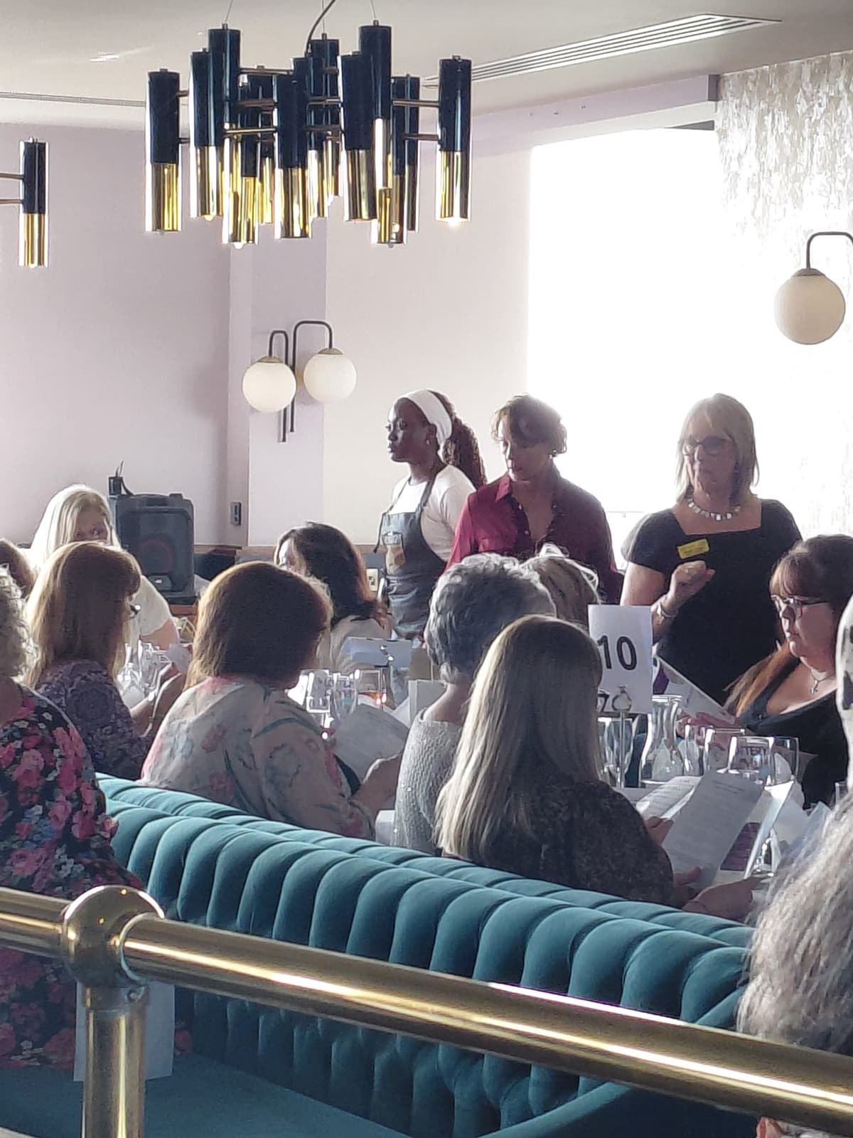 Guests seated at tables in a stylish private dining room with teal banquette seating