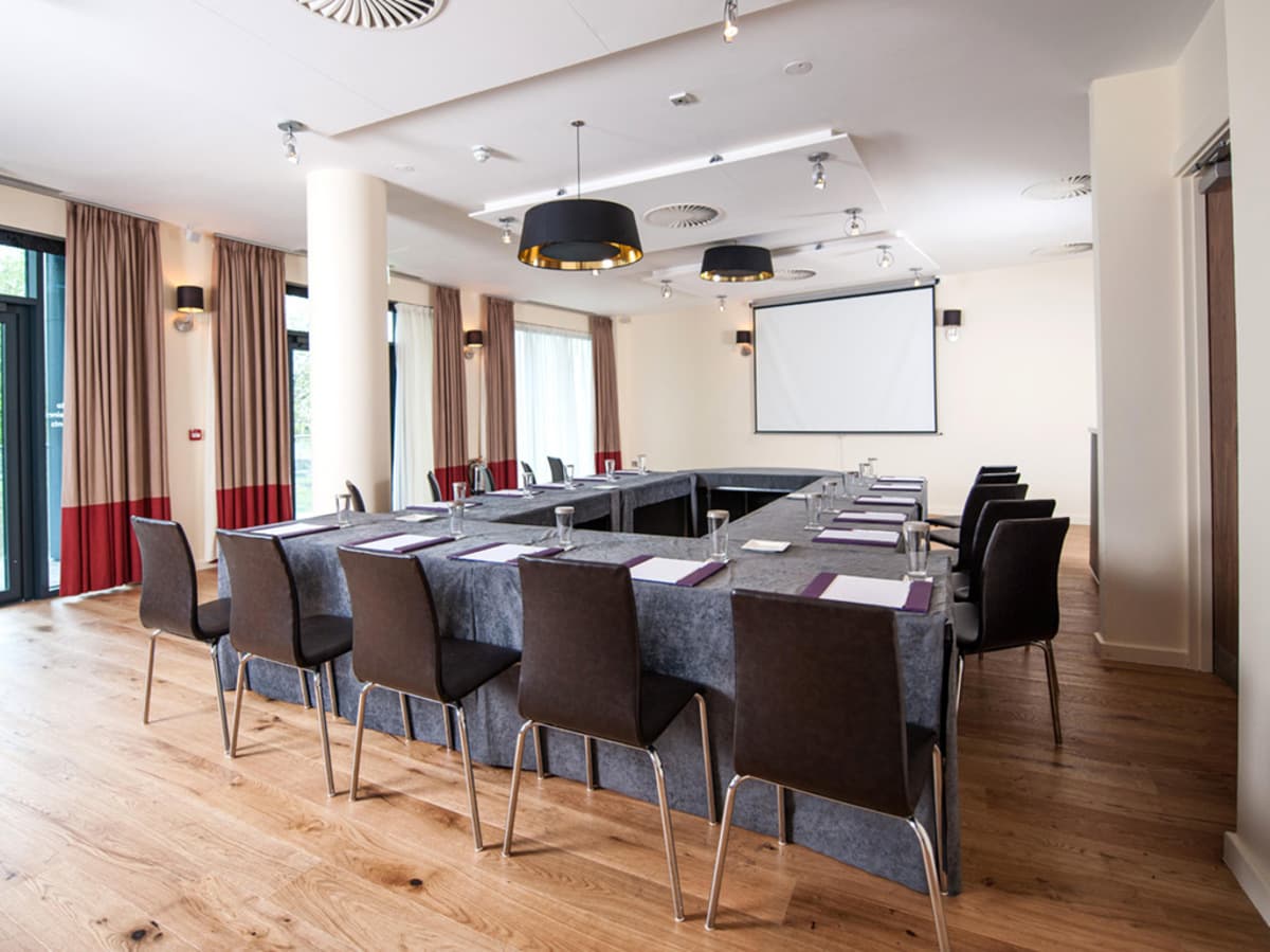 Conference room at Abode Chester set in U-shape with projection screen and wooden floors.