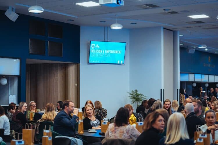 Delegates seated at tables in a conference room with a wall-mounted screen