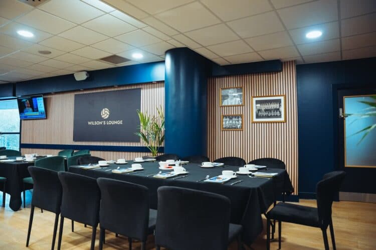 Wilson's Lounge at Accu Stadium with laid tables, dark walls and framed football photographs.