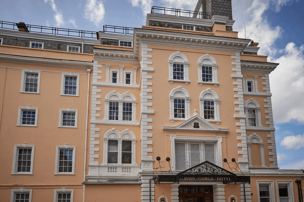 The peach and white Georgian facade of Avon Gorge Hotel in Bristol under blue skies.
