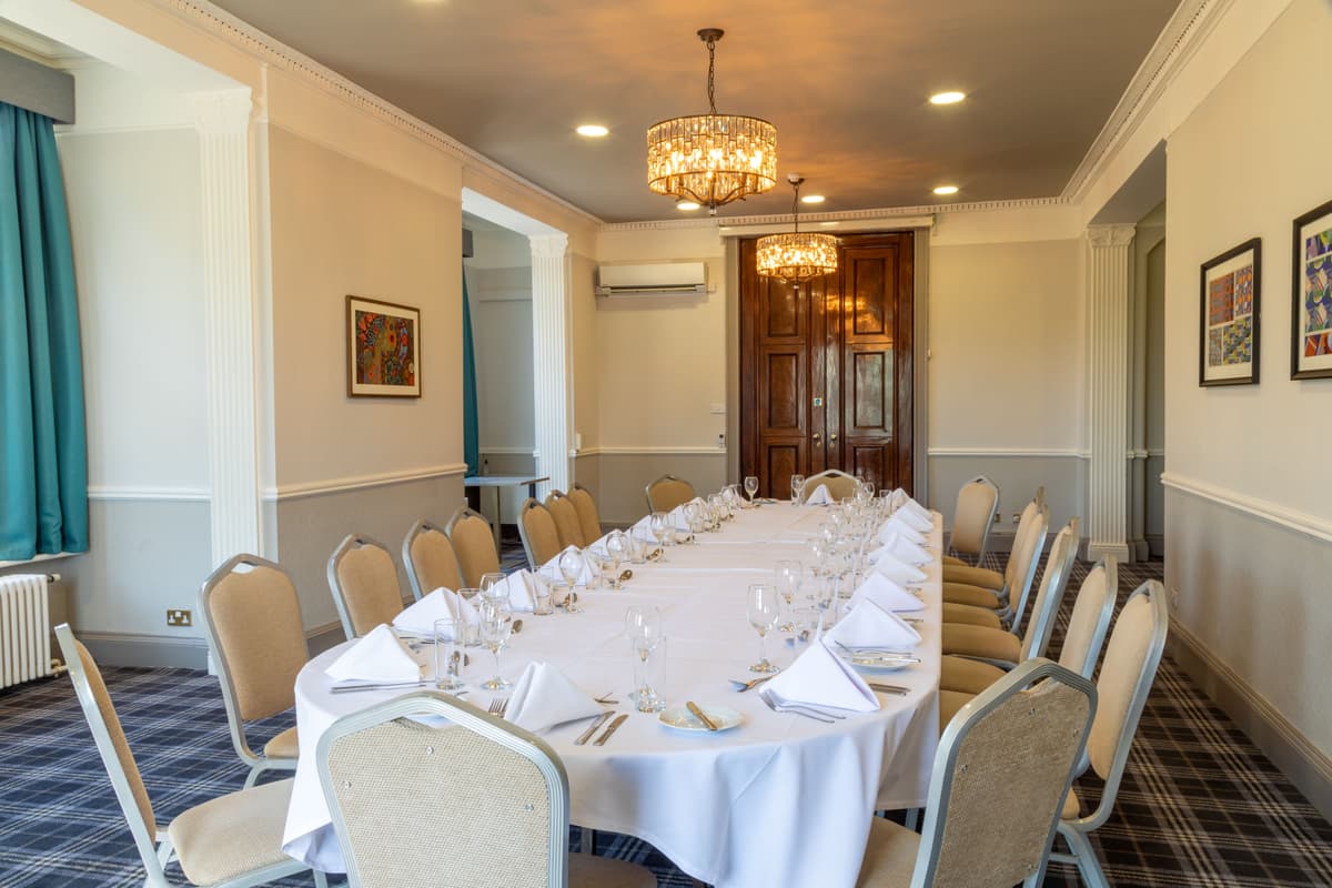 Private dining room laid for a formal dinner with white linen and glassware at Chilworth Manor Hotel.