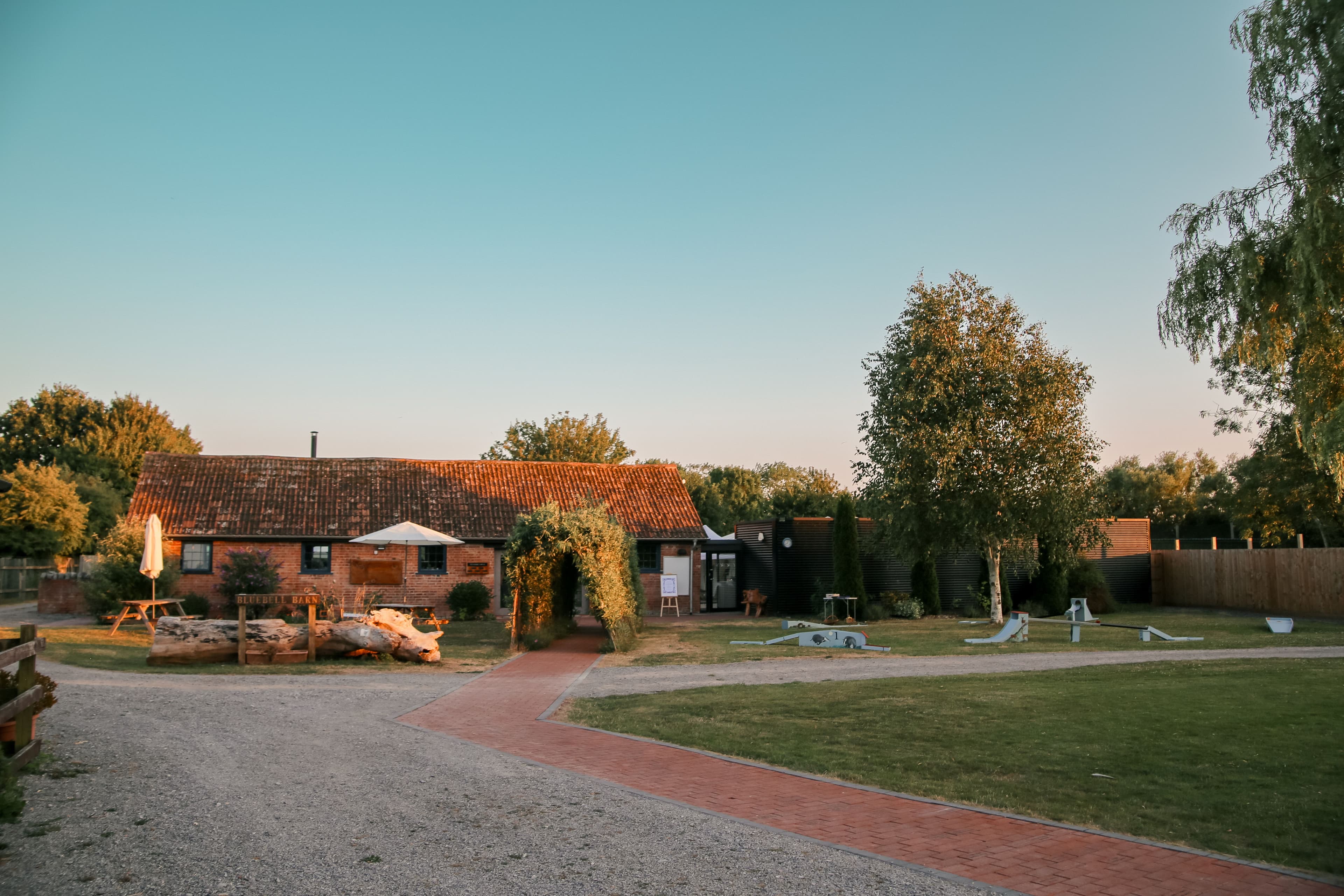 Exterior of Bluebell Barn at golden hour with lawned grounds and brick pathway.