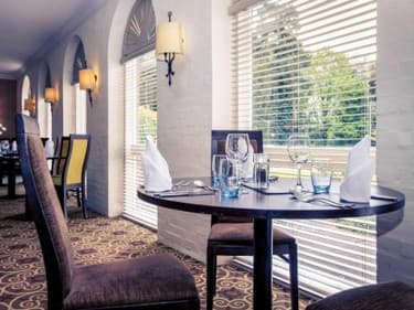 Elegantly laid dining table by bright windows in Brandon Hall Hotel restaurant.