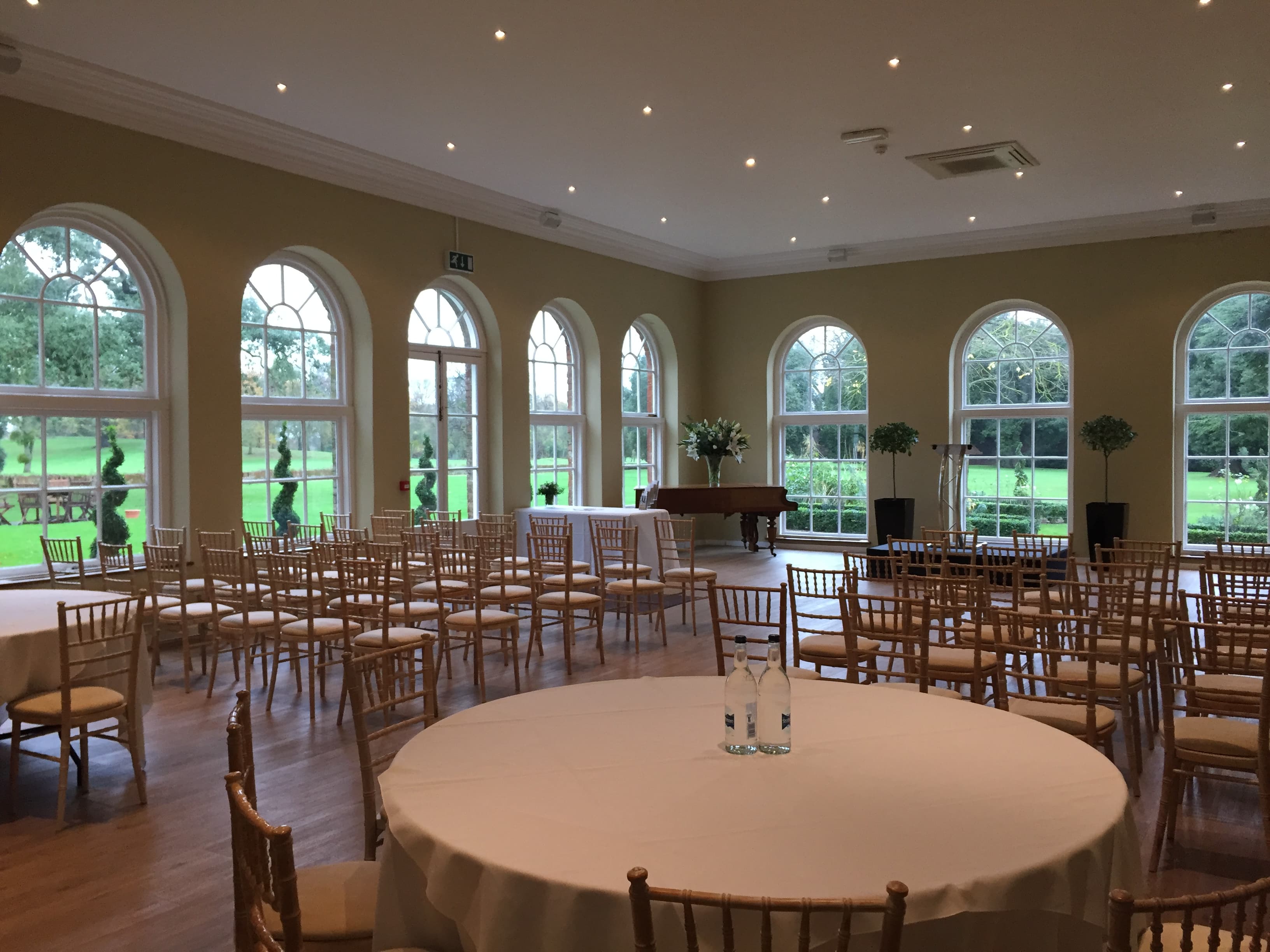 Bright orangery at Braxted Park Estate set with chiavari chairs and a grand piano.