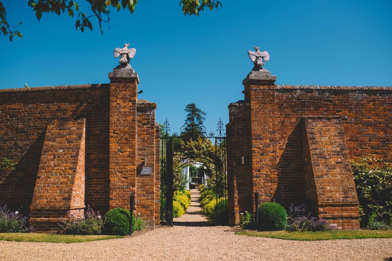 Ornate iron gates set into a red brick walled garden at Braxted Park Estate.