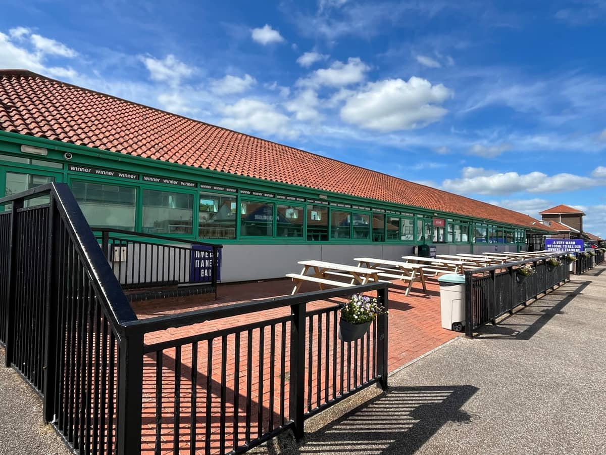 Exterior terrace with picnic benches at Brighton Racecourse on a sunny day.