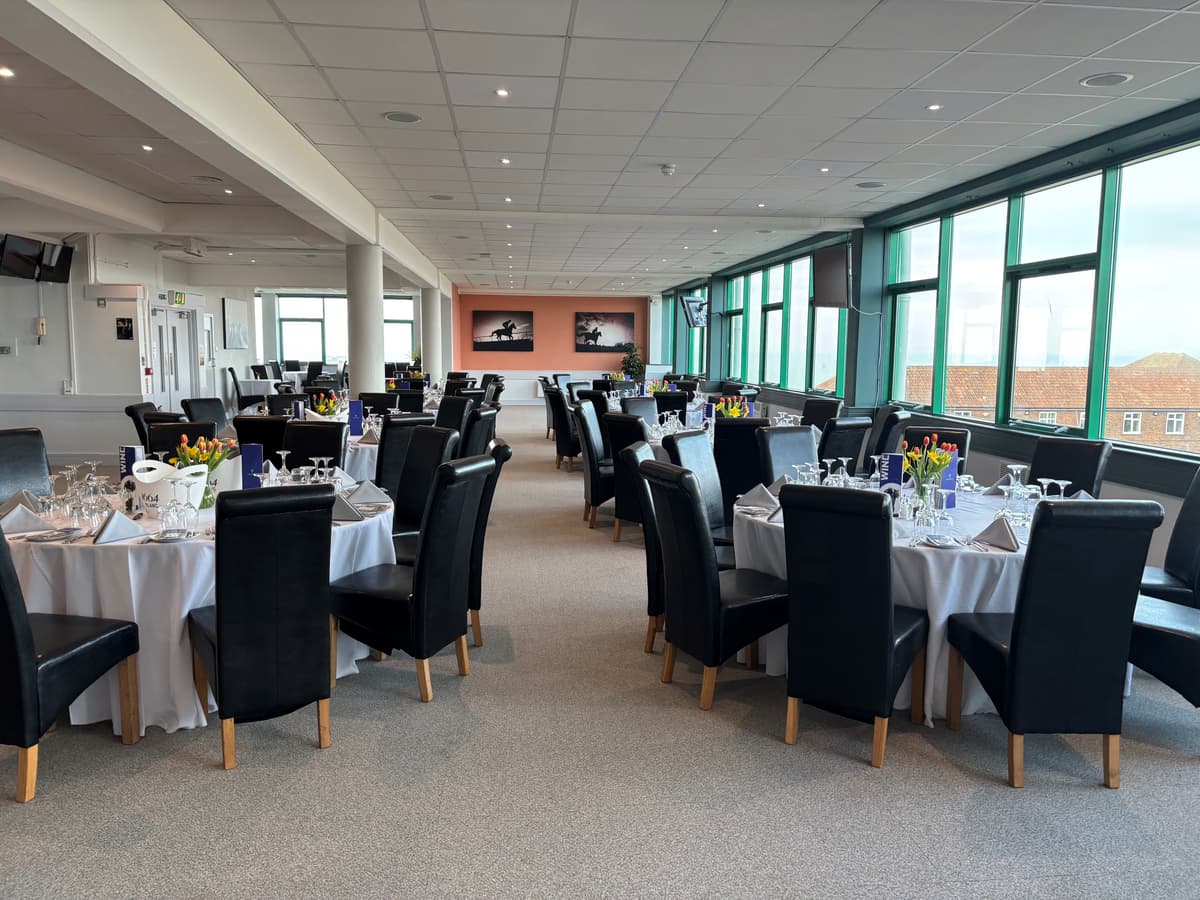 Laid tables with tulips and wine glasses in a racecourse hospitality dining room.