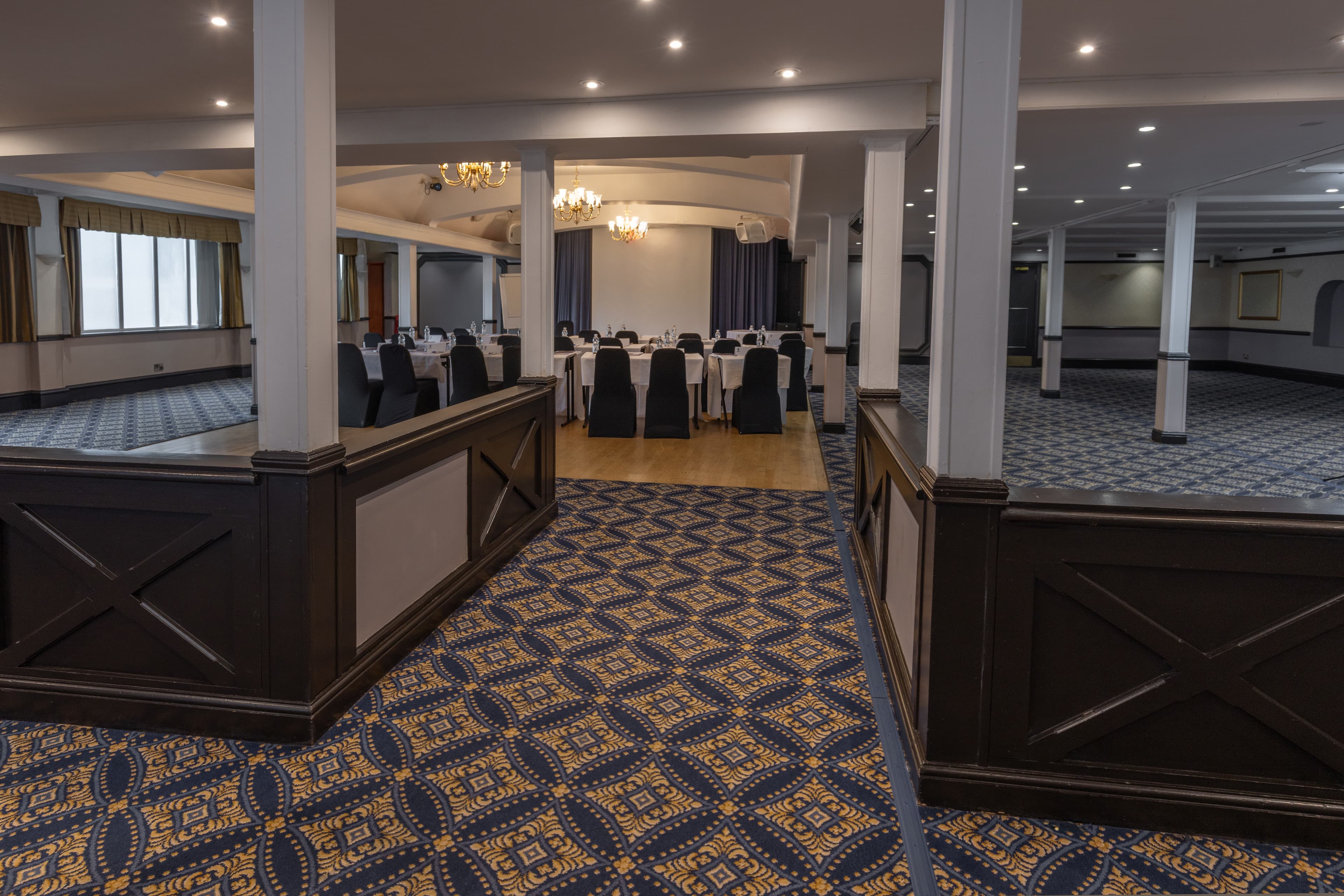 Large function room at Calcot Hotel with patterned carpet, chandeliers and conference table layout.