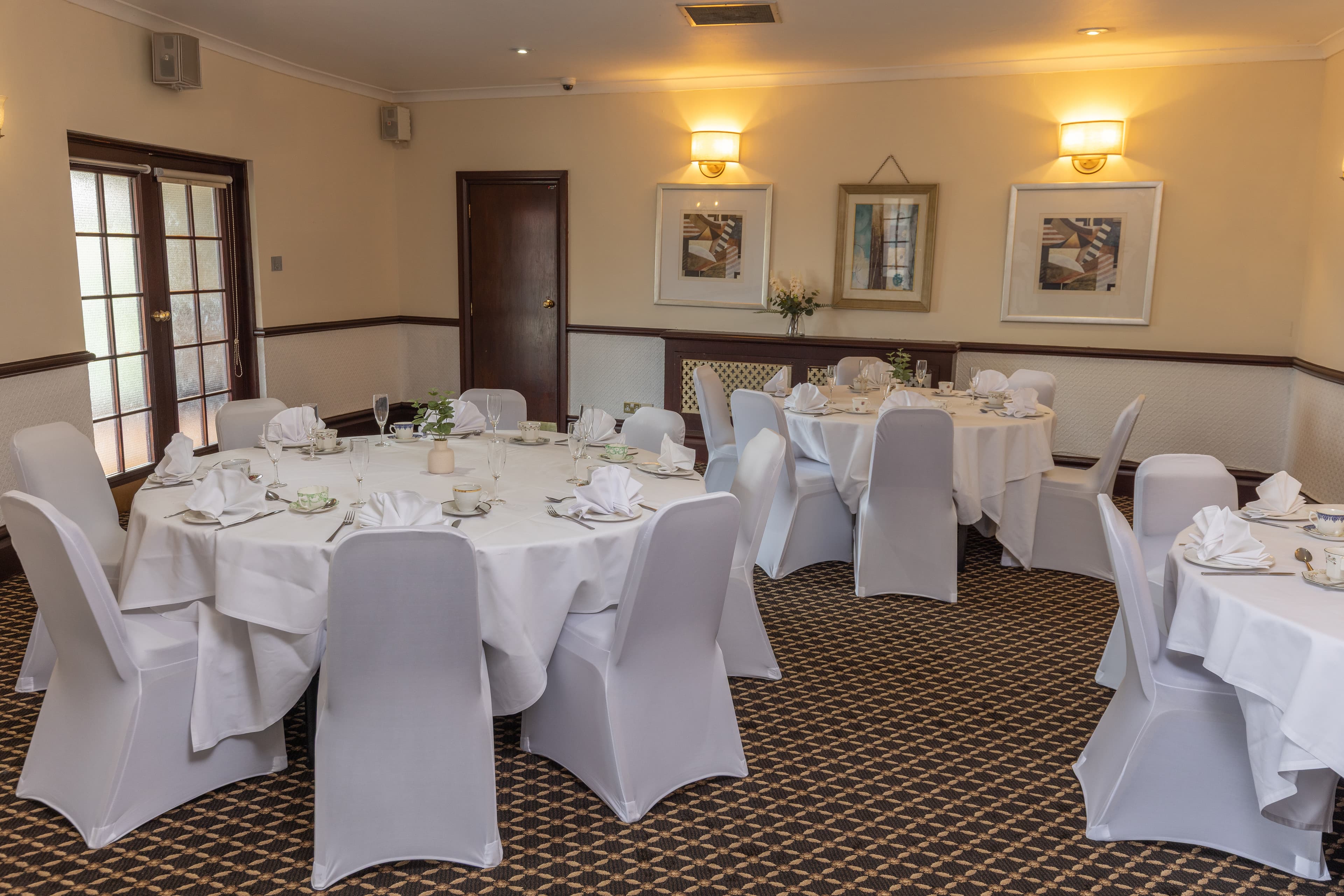 Private dining room at Calcot Hotel with round tables set in white linen and chair covers.