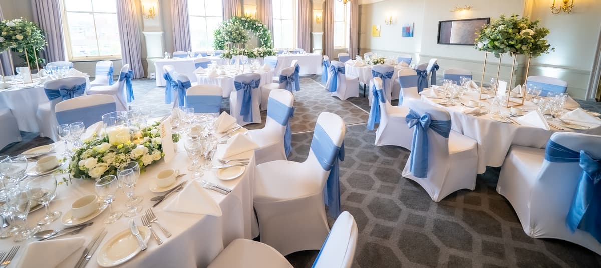 Assembly room set with white chair covers and blue sashes.
