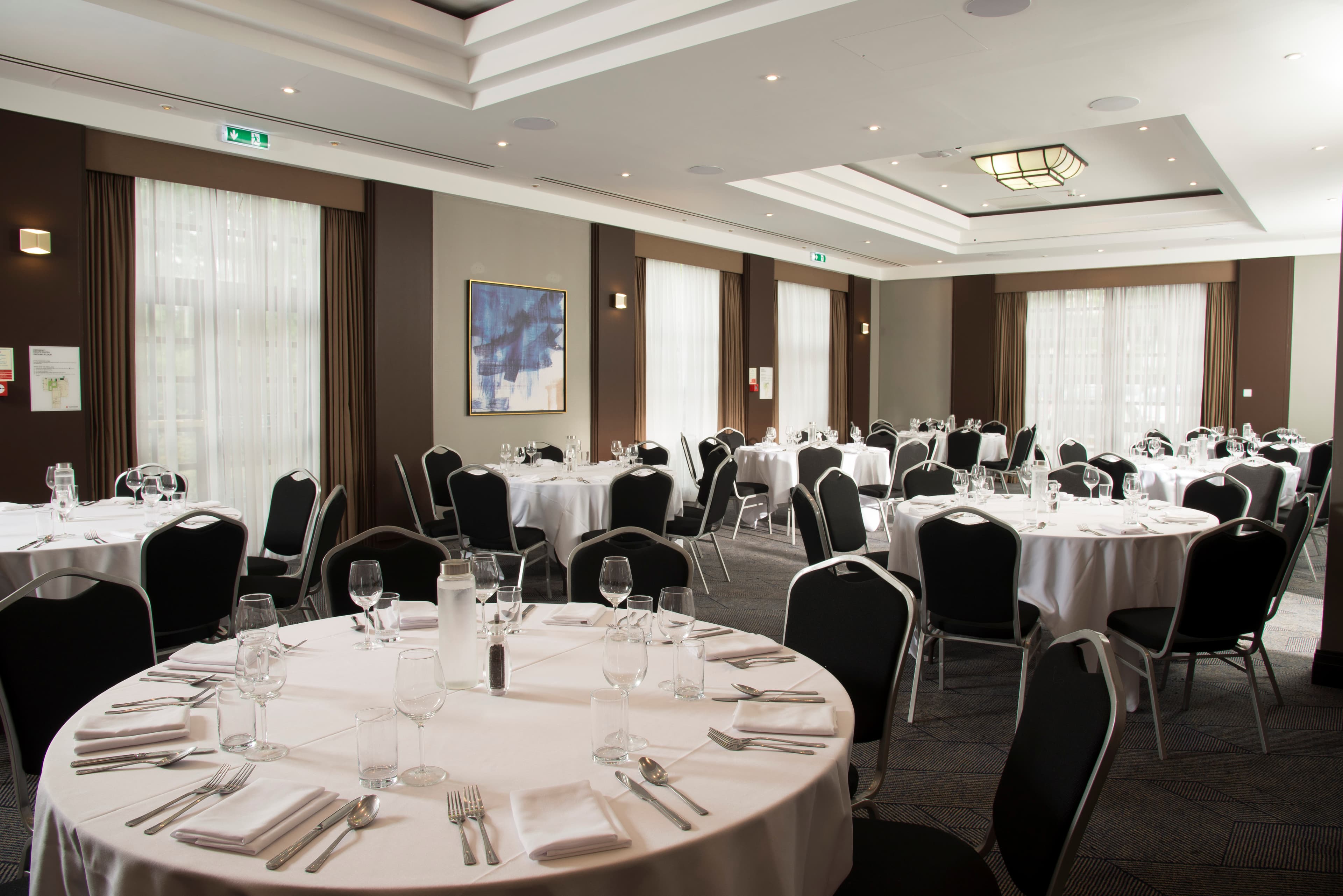 Banqueting room at Crowne Plaza Solihull with round tables laid for a formal dinner.