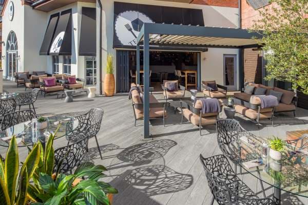 Sunny outdoor terrace with rattan sofas, ornate metal chairs and a pergola