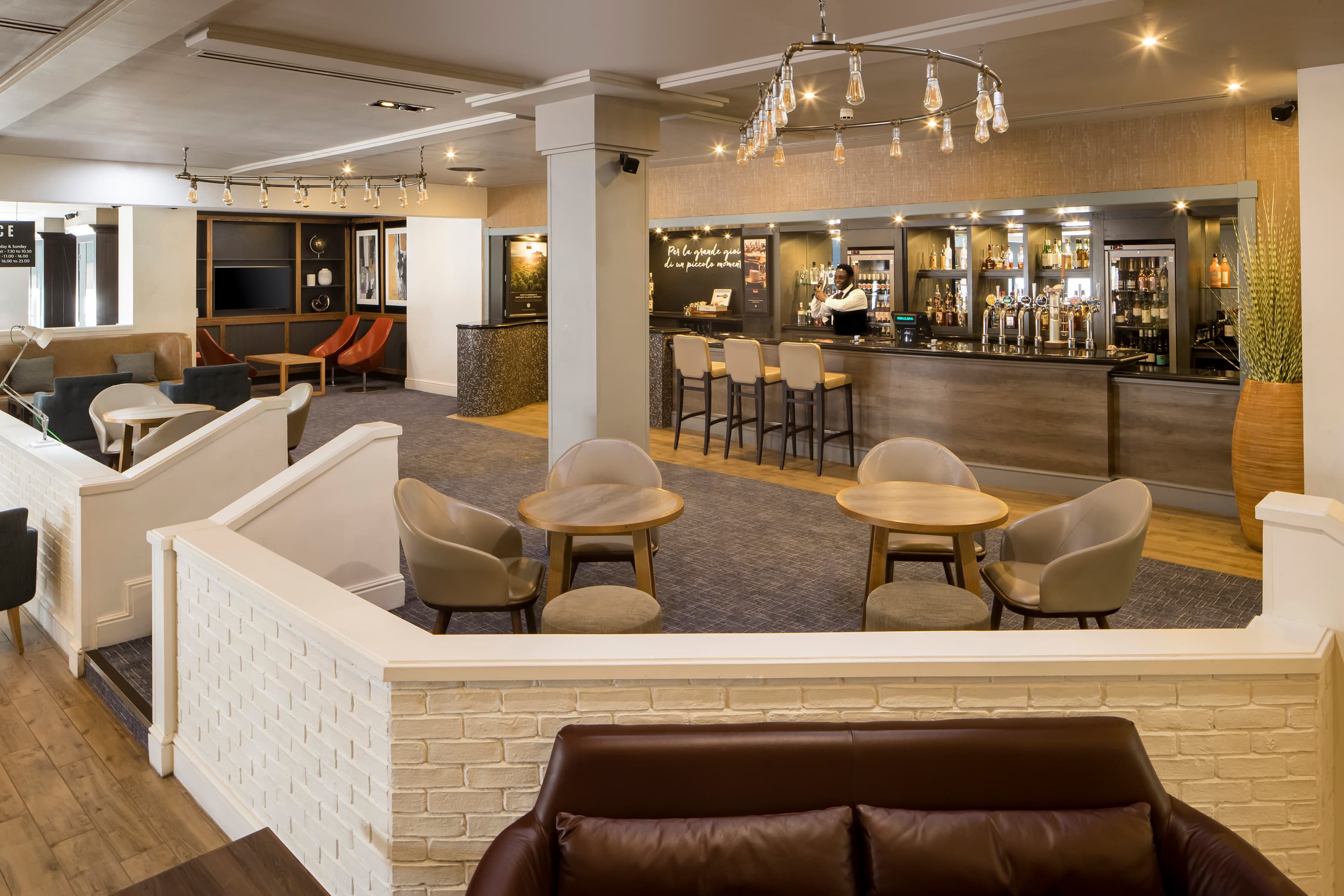 Hotel bar lounge area with seating, draught taps and a bartender at Crowne Plaza Solihull.