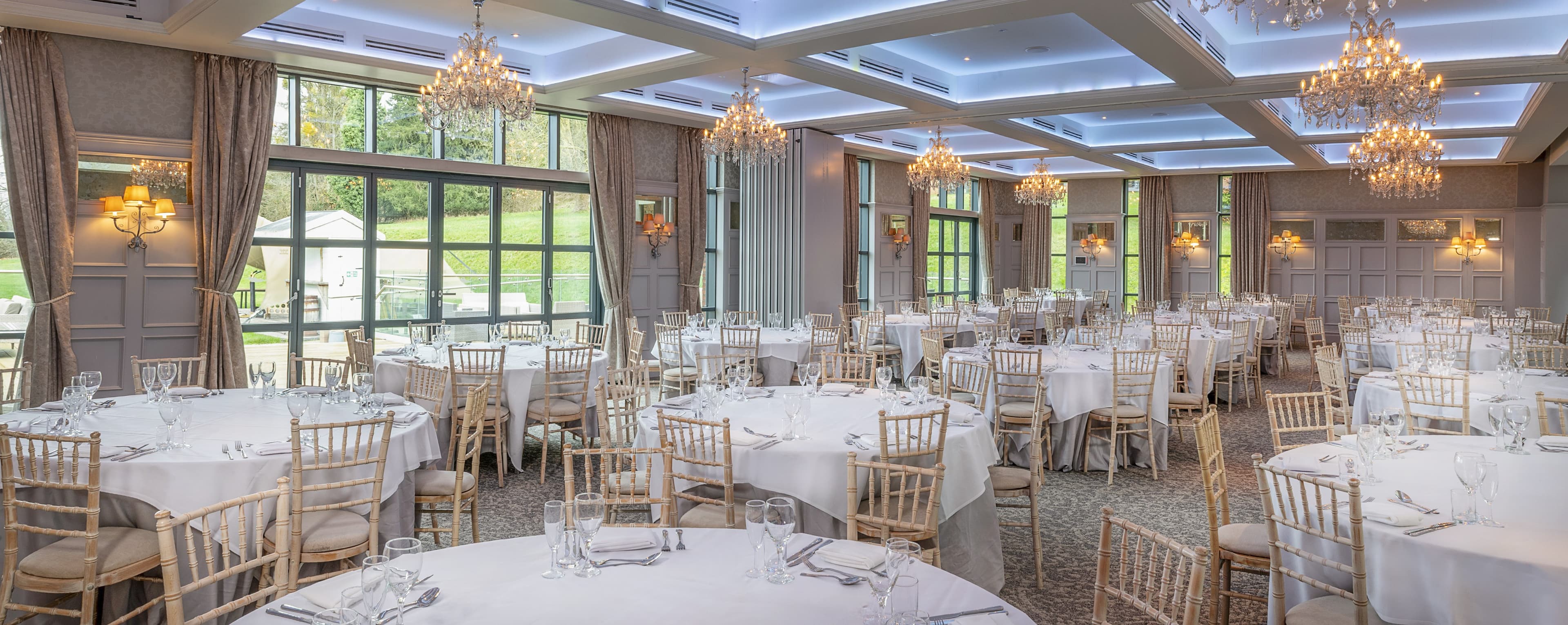 Ballroom at De Vere Latimer Estate laid for a formal seated dinner with chandeliers