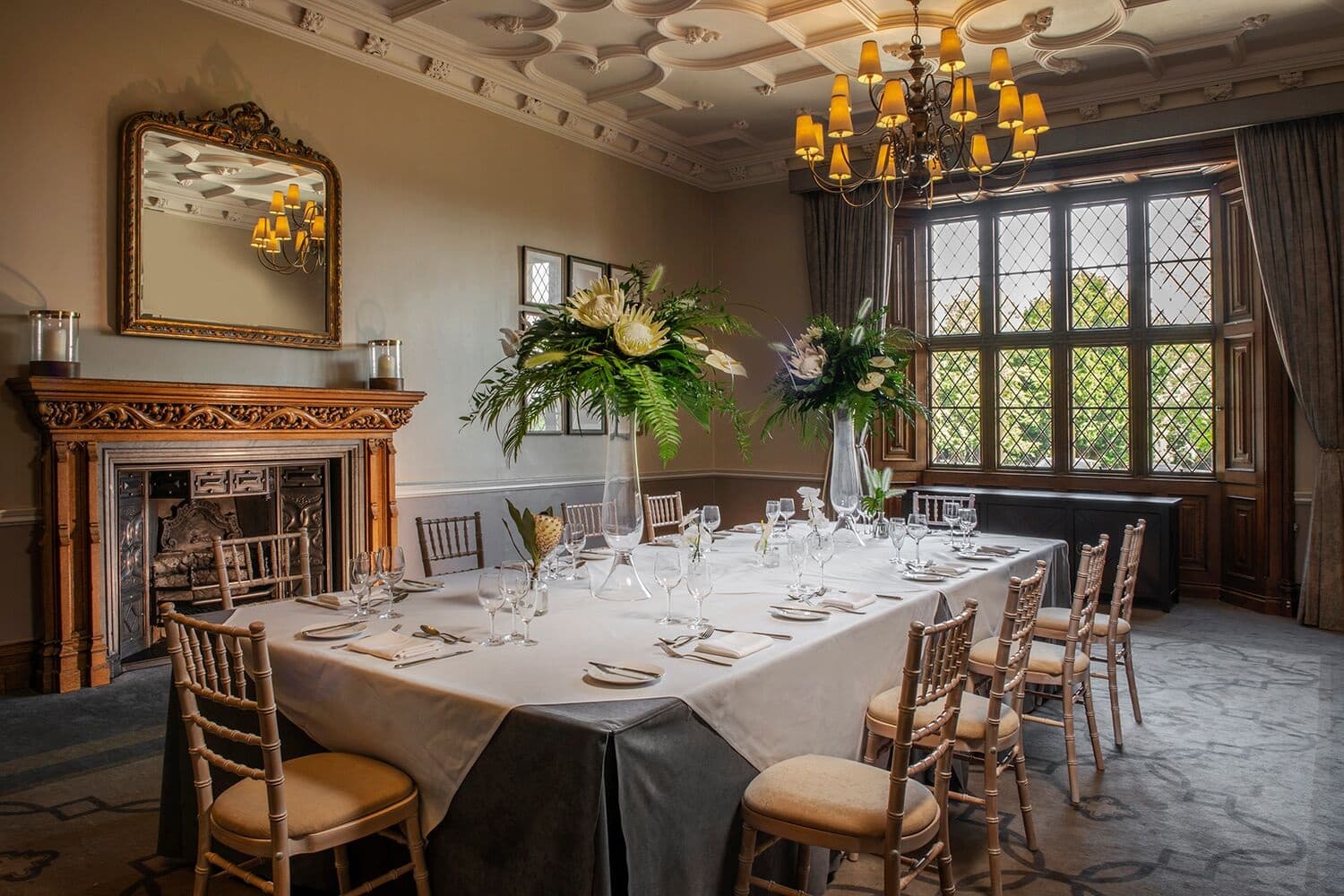 Private dining room with long banquet table, ornate fireplace and leaded windows at De Vere Latimer Estate.
