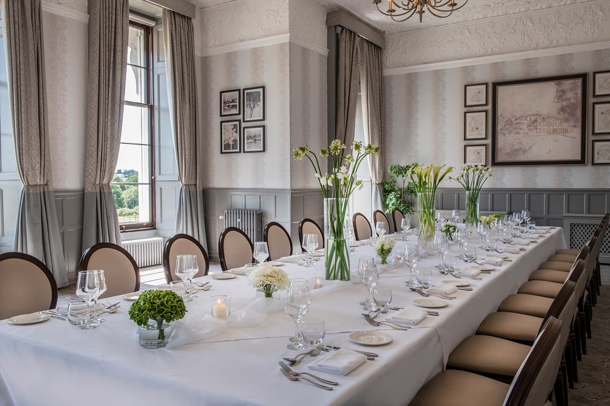 Formal private dining room laid for a banquet with white floral centrepieces and candlelight.
