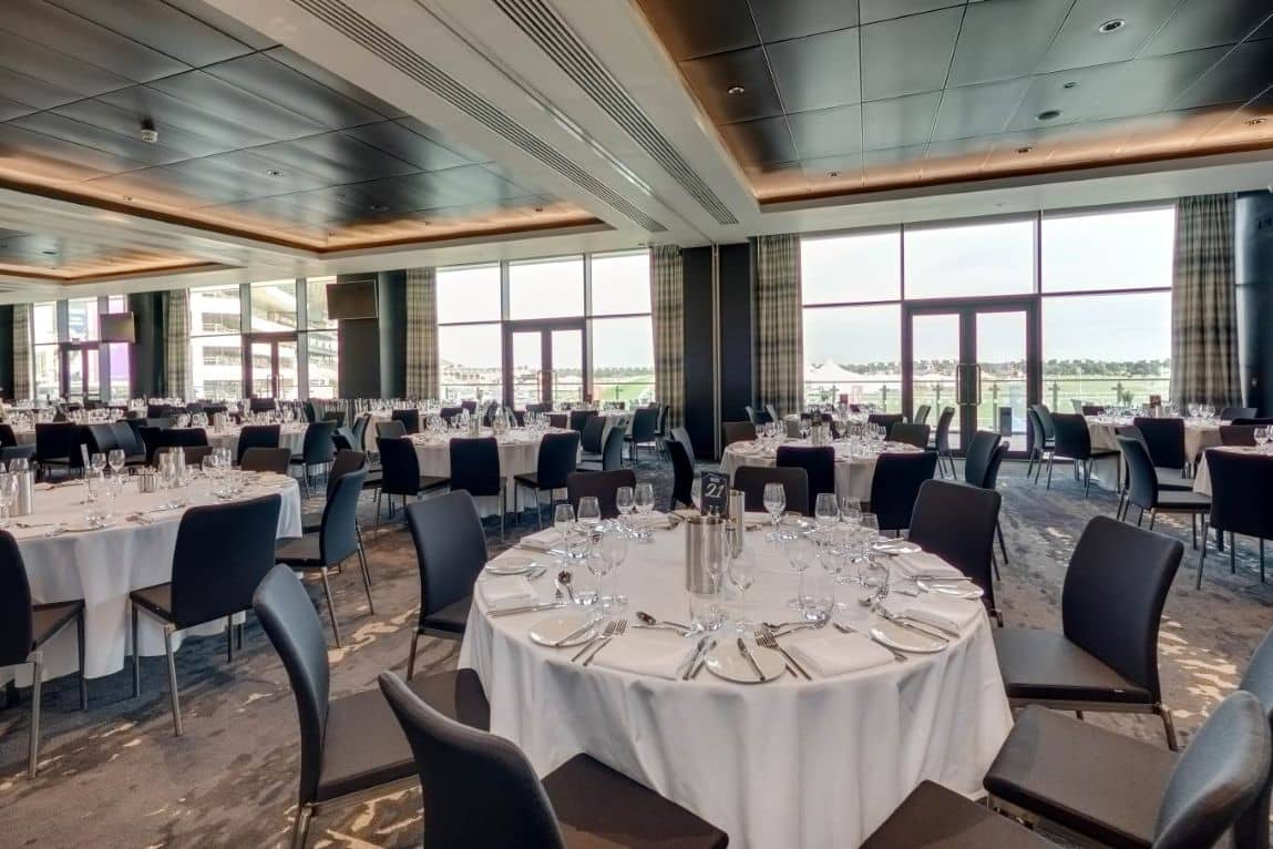 Banqueting room at Doncaster Racecourse with round tables set for dining and trackside views.