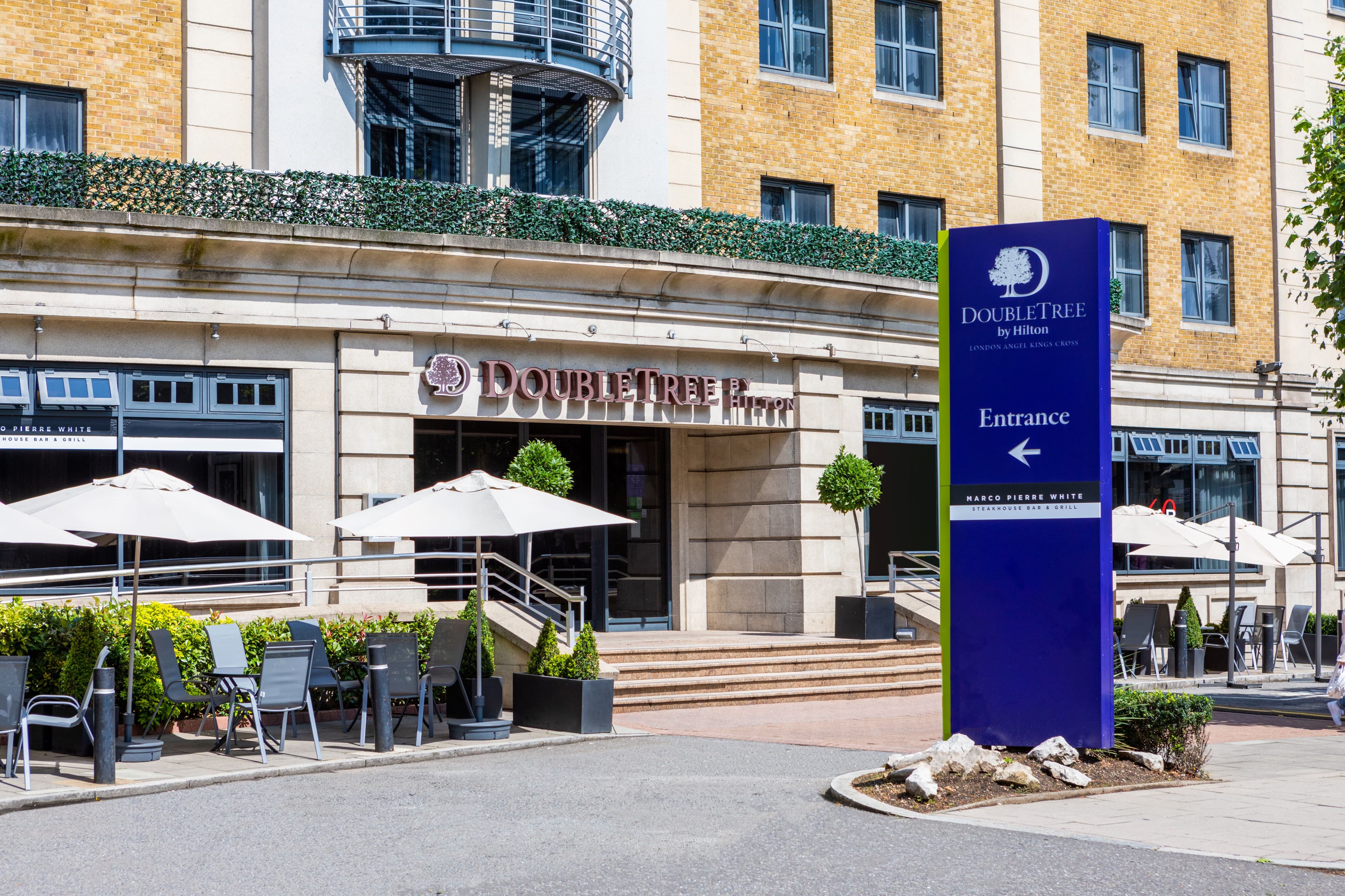 Exterior of DoubleTree by Hilton Angel Kings Cross with outdoor seating and entrance signage.
