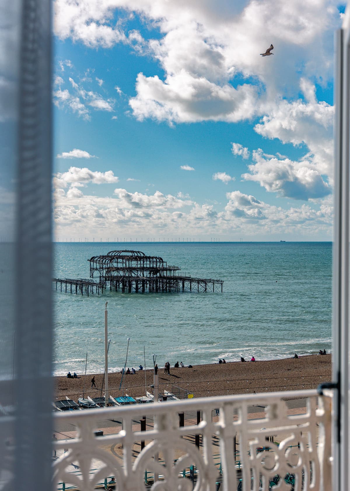 Sea view from a hotel balcony overlooking Brighton's derelict West Pier and shingle beach.