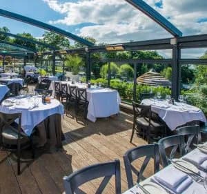 Glass-roofed terrace dining area with white-clothed tables overlooking a garden at Cadbury House.