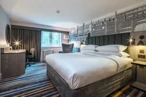 Double king bed room with bold headboard, patterned carpet and decorative wall art.