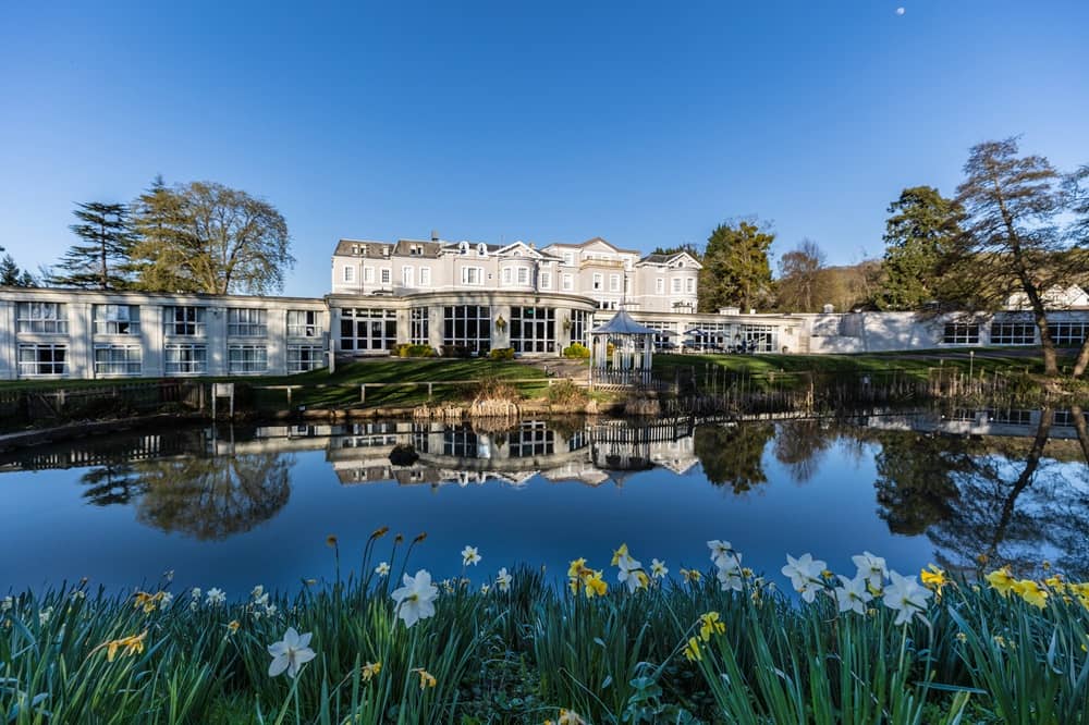 Exterior of the hotel reflected in a lake with daffodils in the foreground