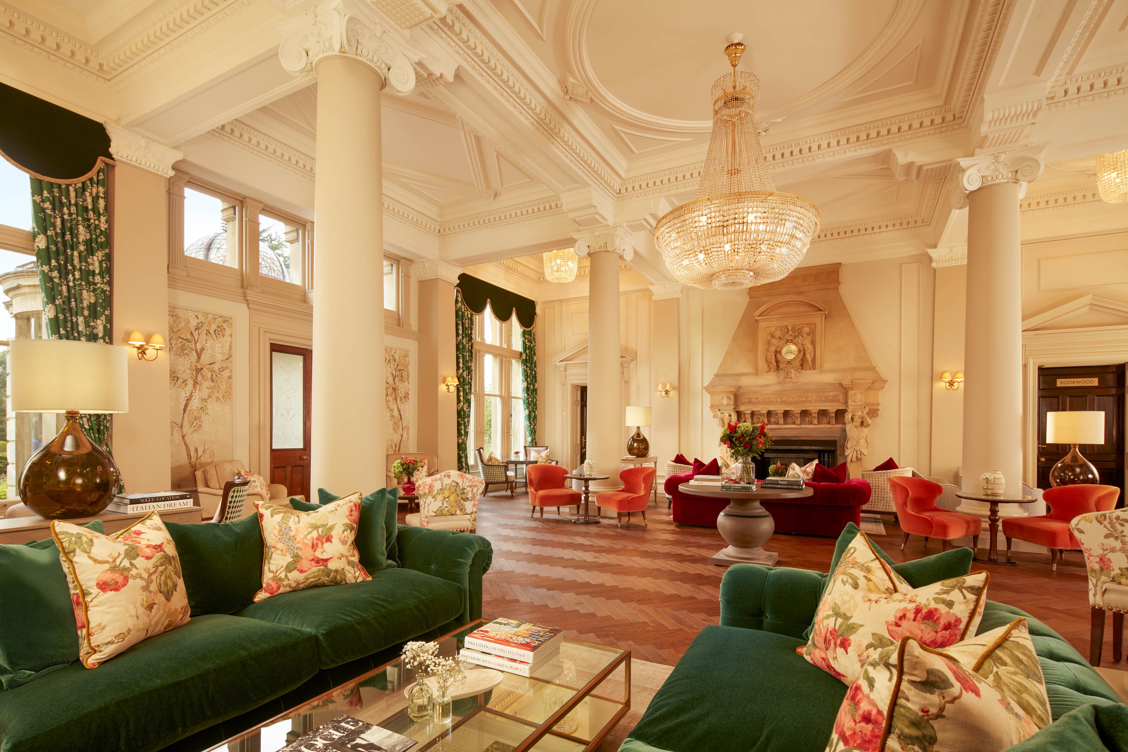Elegant lounge with teal walls, gilt-framed paintings, patterned armchairs and an afternoon tea setting