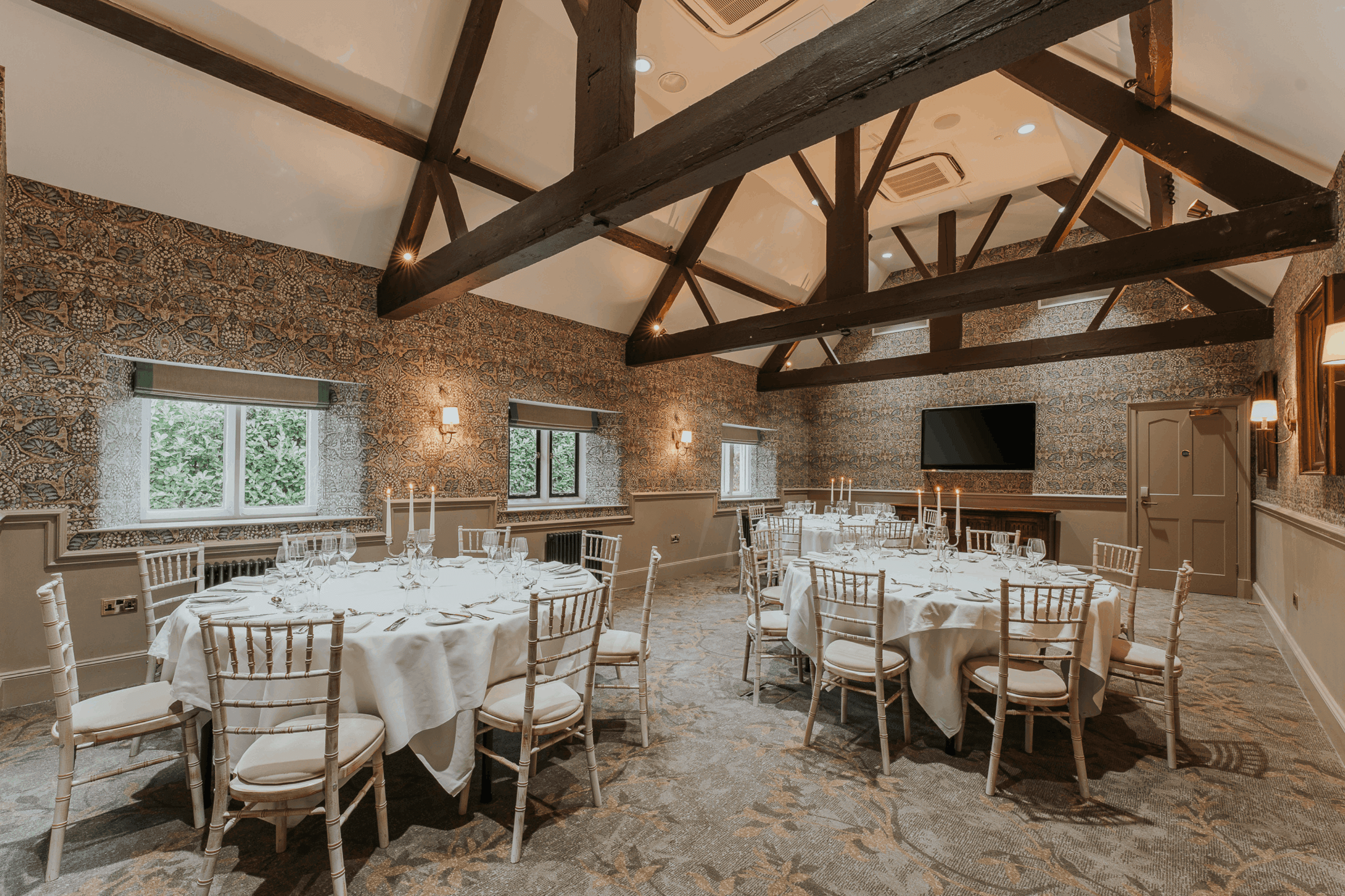 Private dining room with round tables, chiavari chairs and exposed timber beams at Ellenborough Park.