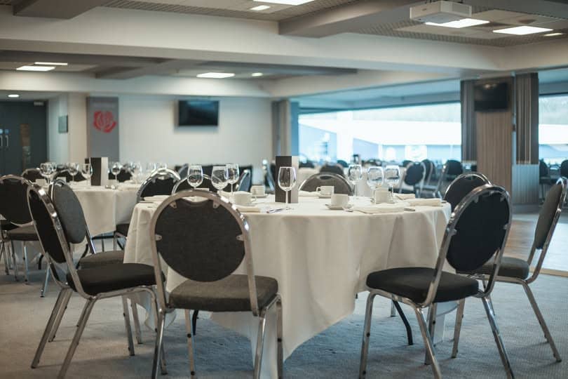 Round banquet tables laid with white linen and wine glasses in a conference suite.