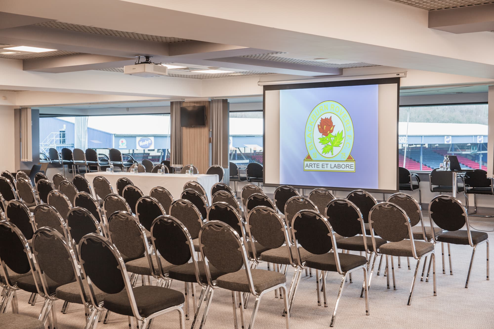Conference room set in theatre style with Blackburn Rovers crest on projection screen.