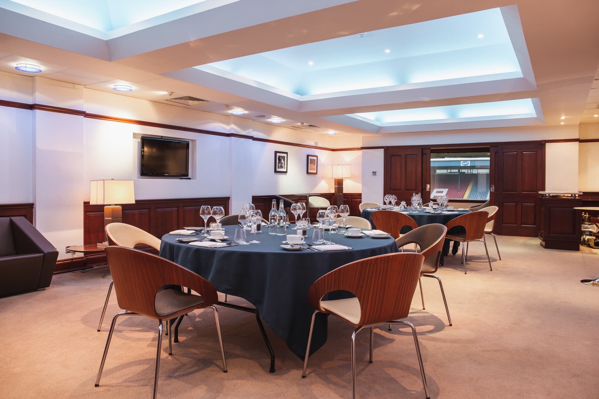 Private dining room at Ewood Park with round tables, glassware and stadium views.