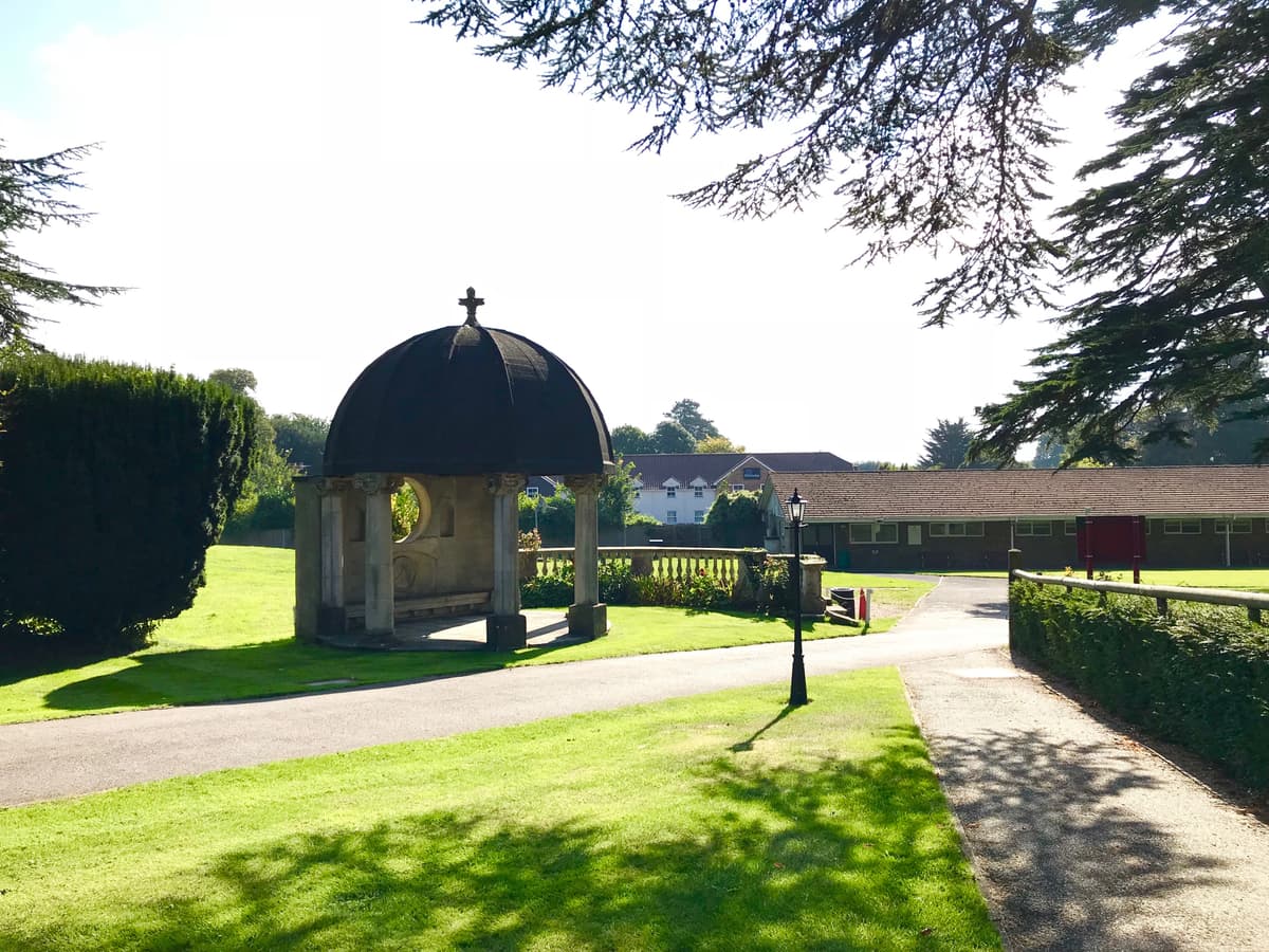 Stone domed pavilion with cross finial set within manicured grounds at Fontwell Park Racecourse.