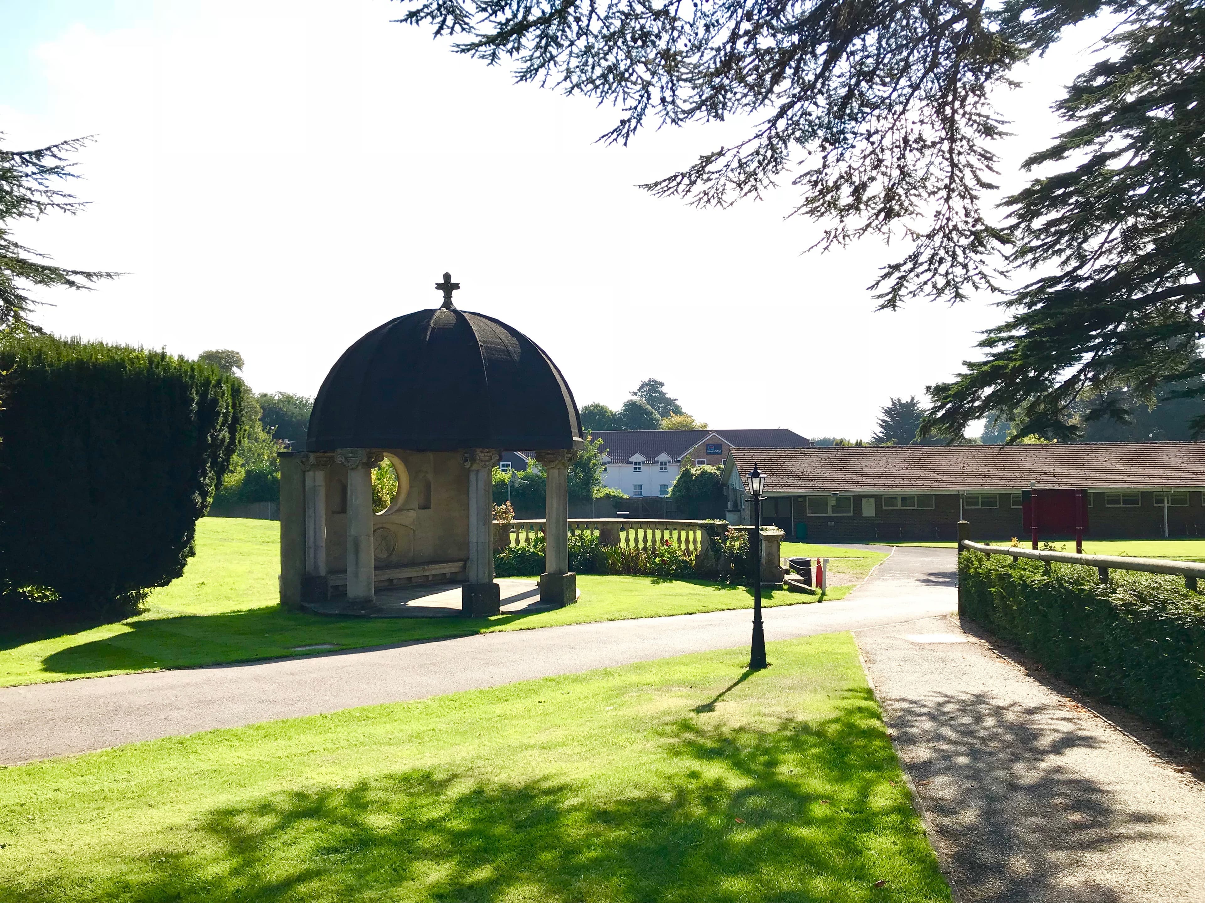 Stone domed pavilion with cross finial set within manicured grounds at Fontwell Park Racecourse.
