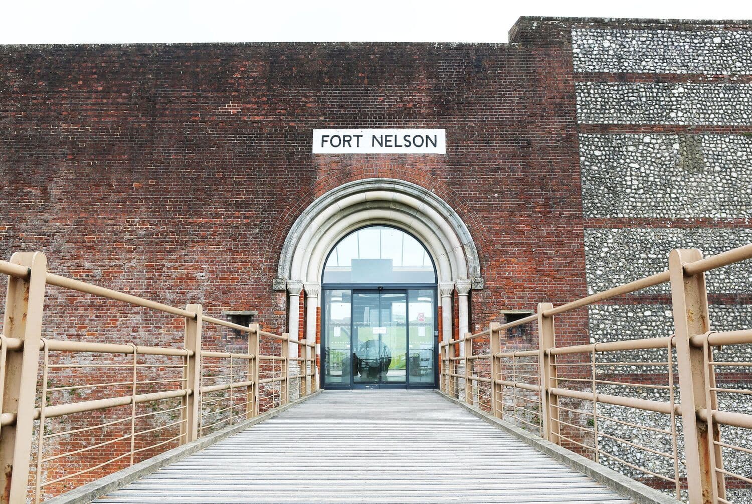 The brick entrance to Fort Nelson with a stone arch and metal walkway.