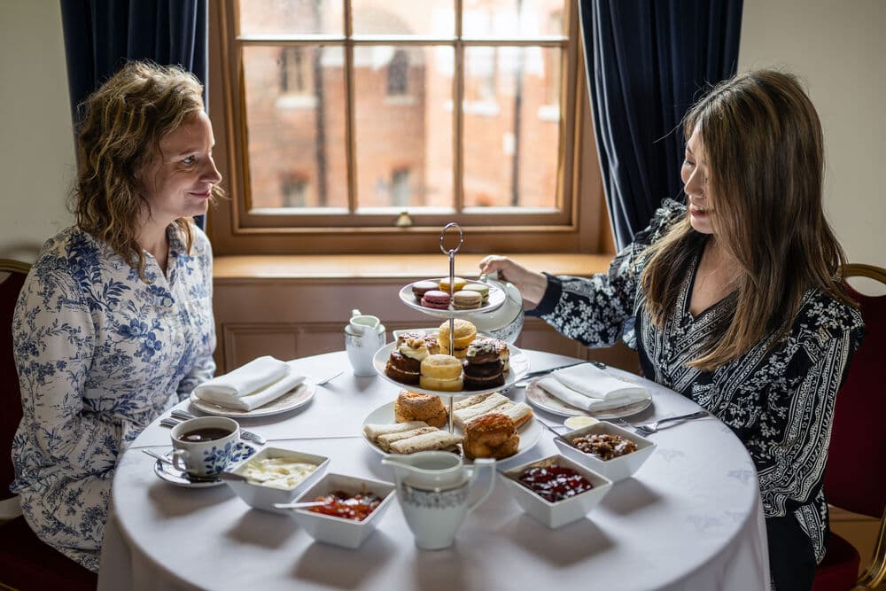 Two women enjoying afternoon tea beside a window at Fort Nelson.