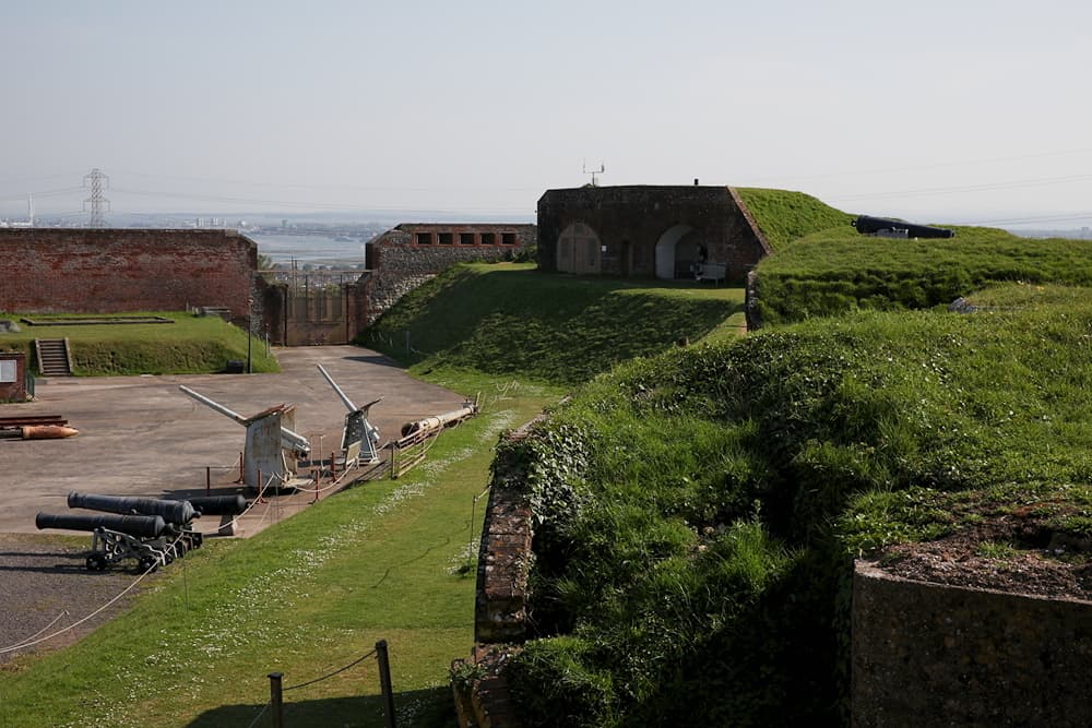 Grass ramparts and historic cannons at Fort Nelson with coastal views beyond.