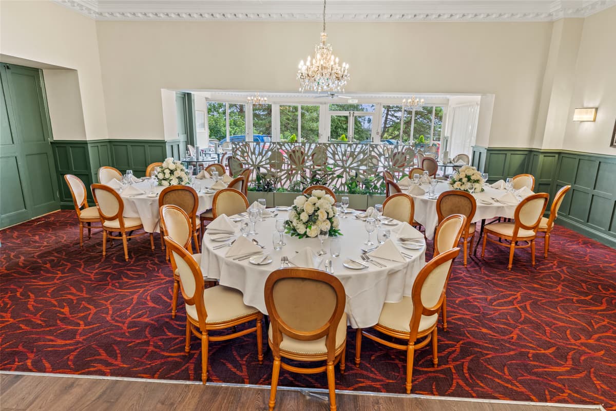 Private dining room at Hermitage Hotel with round tables, white floral centrepieces and chandelier.