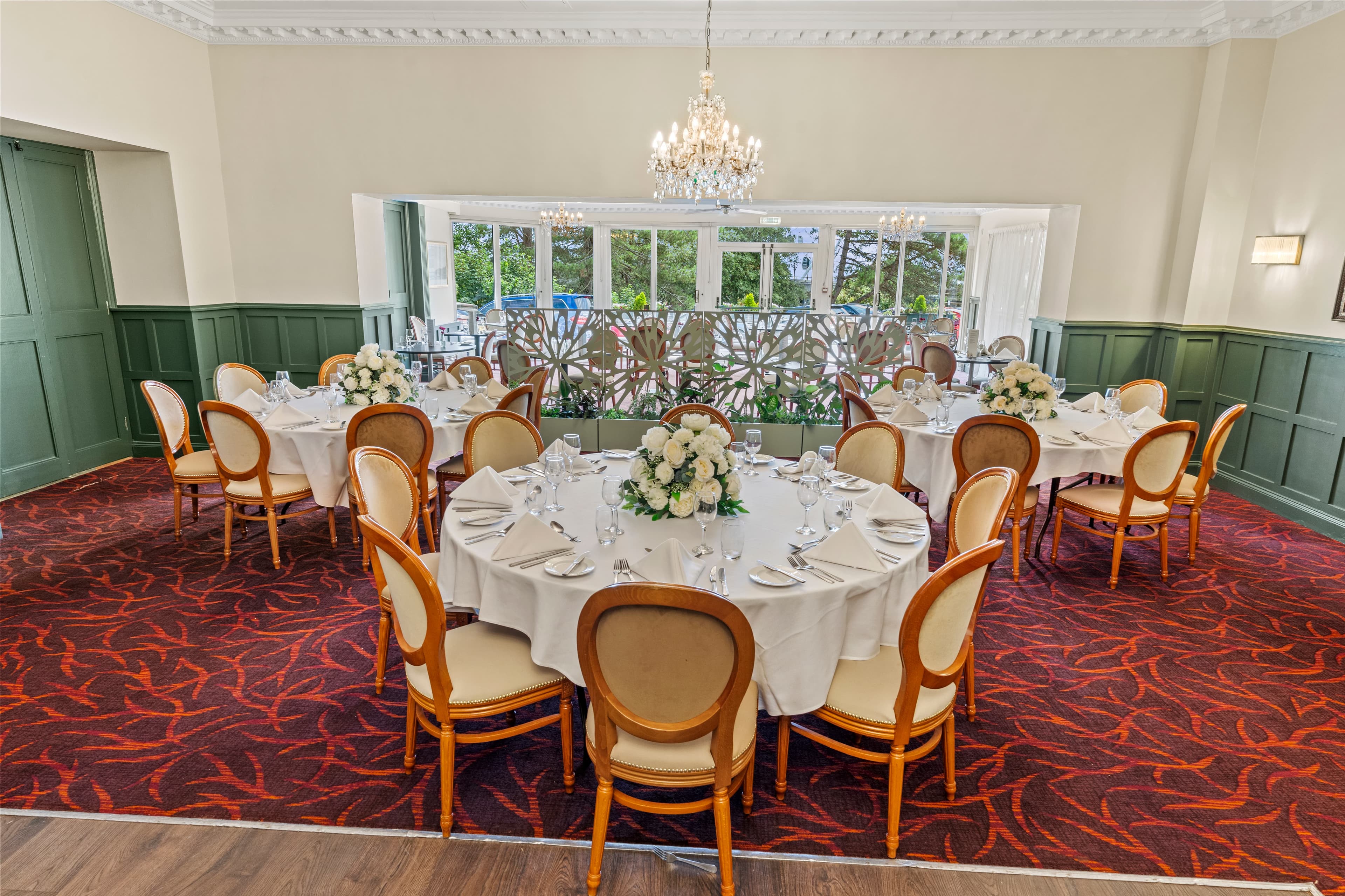 Private dining room at Hermitage Hotel with round tables, white floral centrepieces and chandelier.