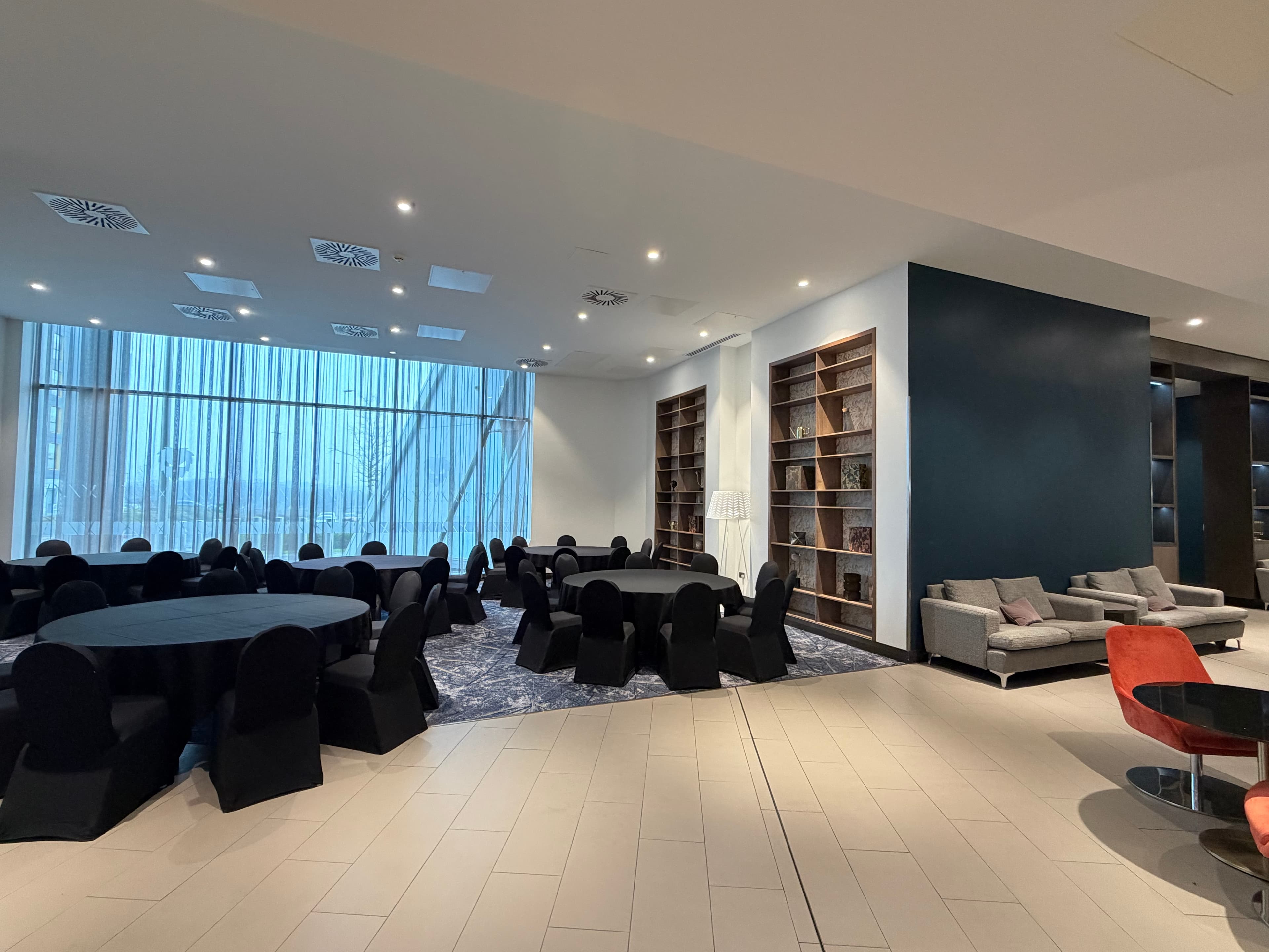 Spacious function room with round black-draped tables, chairs and floor-to-ceiling windows.
