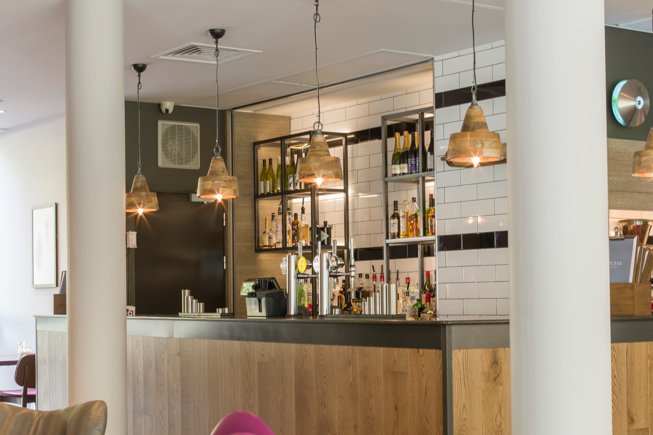 The hotel bar with wood panelling, pendant lights and shelves of spirits and wine bottles.