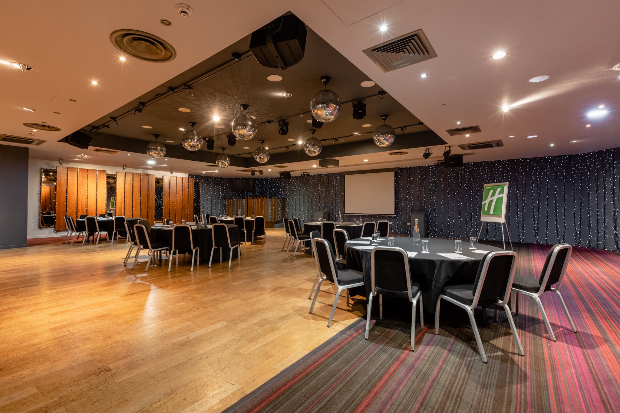 Ballroom at Holiday Inn Aberdeen West set for a conference with round tables and disco balls overhead