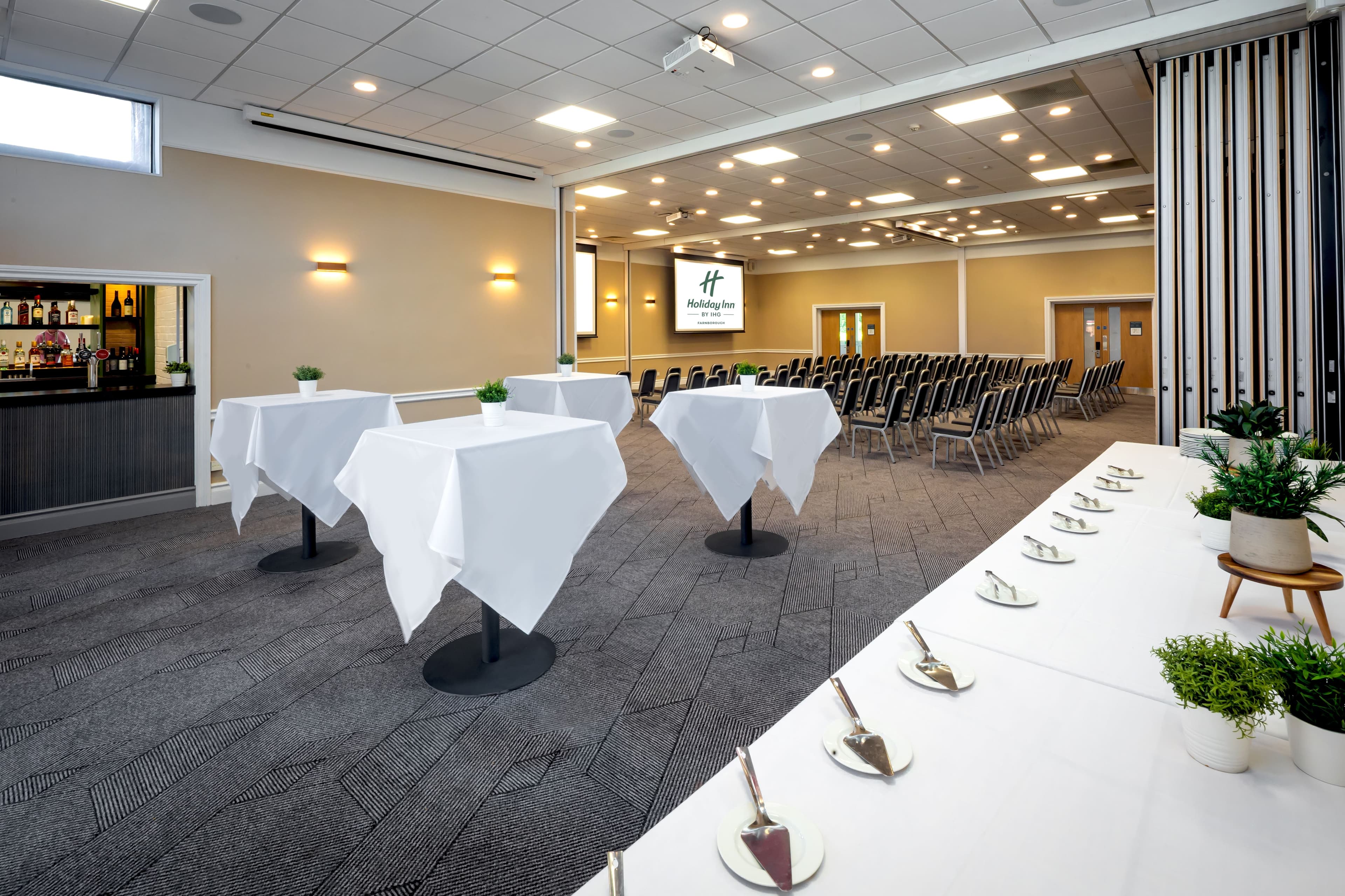 Large conference room at Holiday Inn Farnborough with theatre seating, poseur tables and a bar.