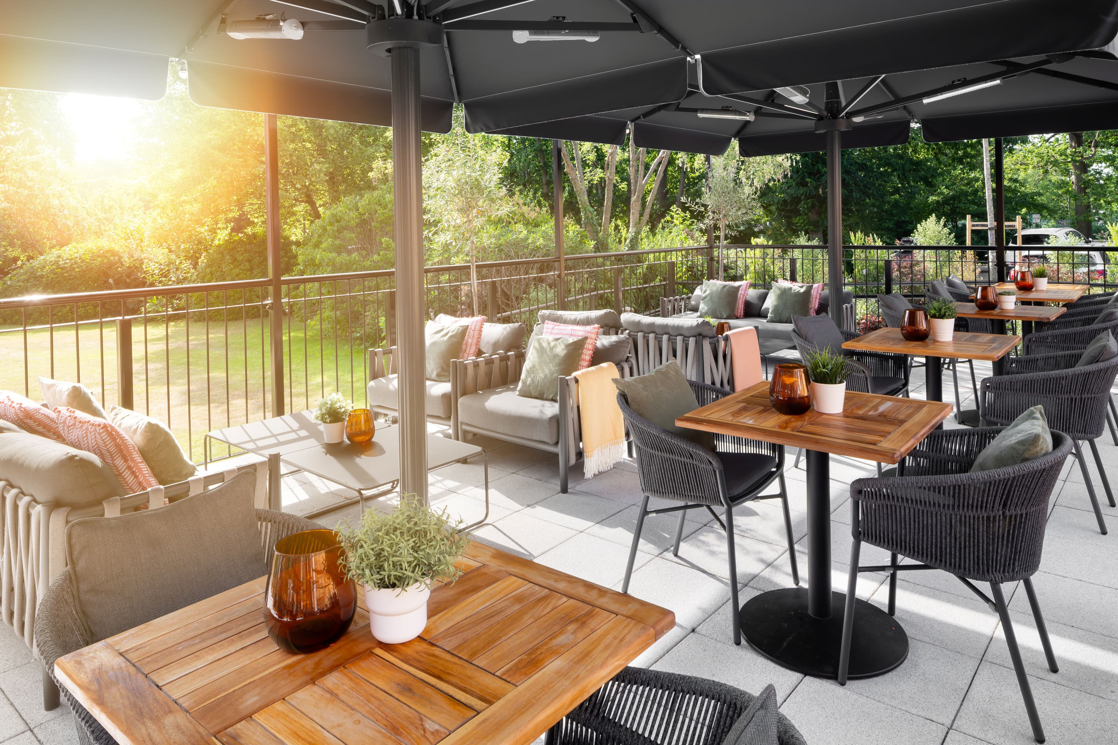 Sunny terrace at Holiday Inn Farnborough with teak tables, rattan chairs and lounge seating
