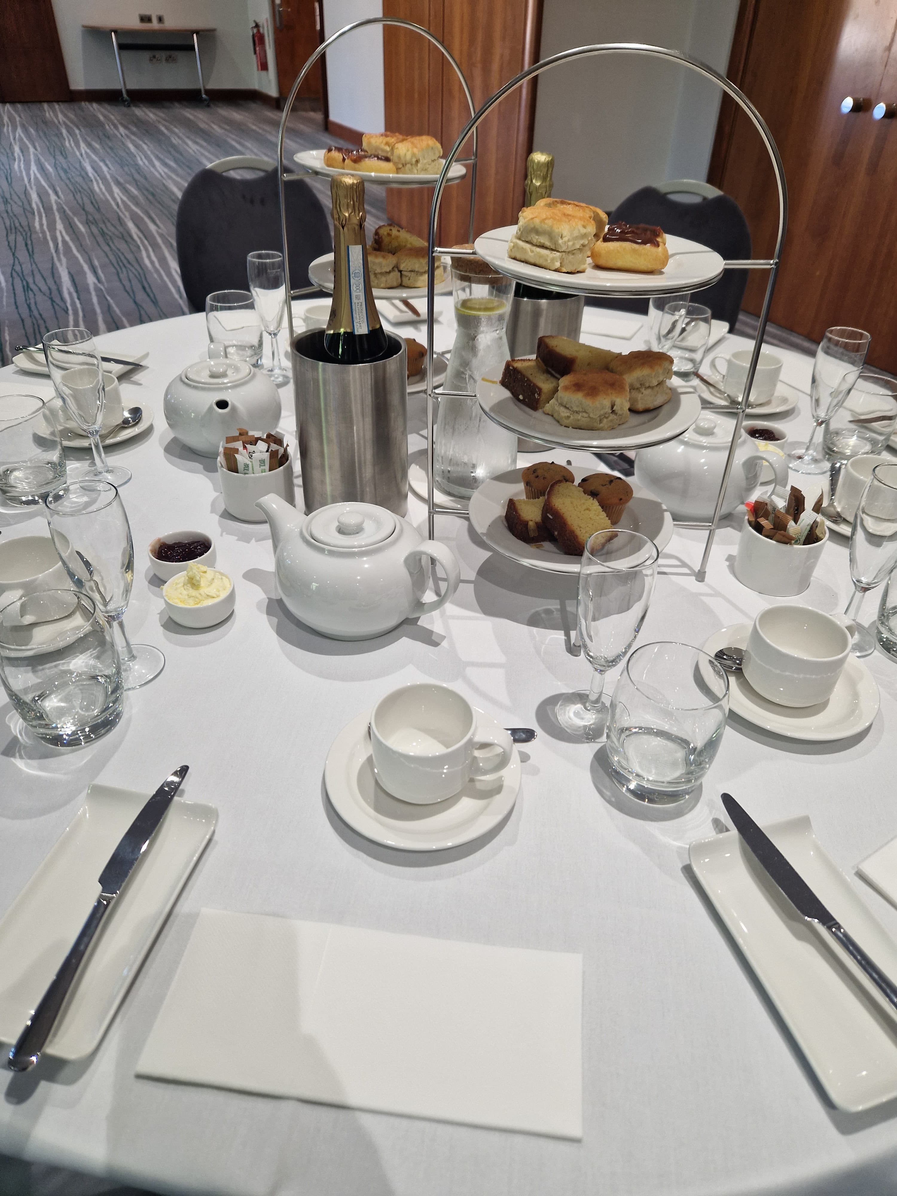 Afternoon tea spread with scones, cakes and champagne on a round table.