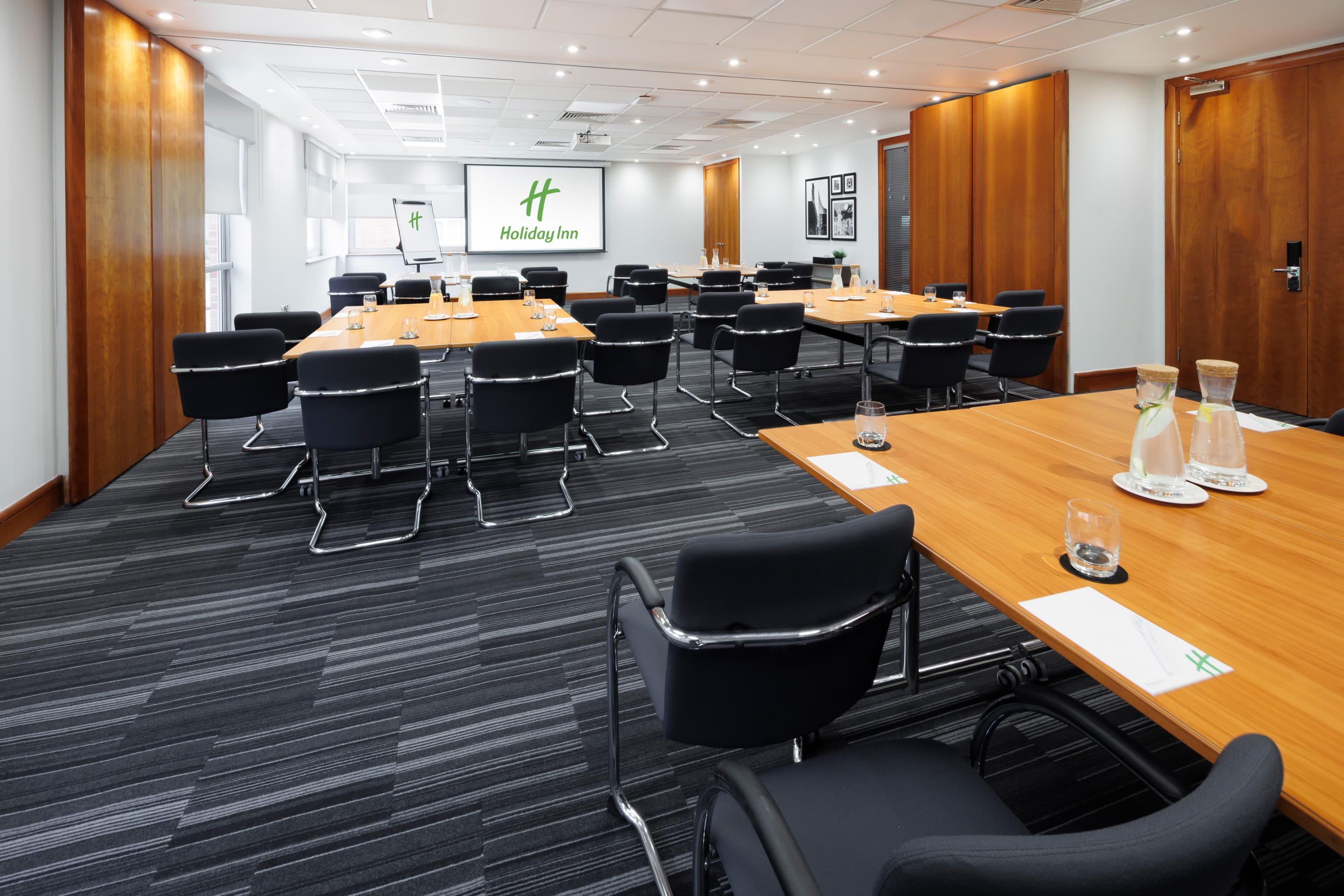 U-shaped conference room at Holiday Inn Reading South with black chairs and projection screen.