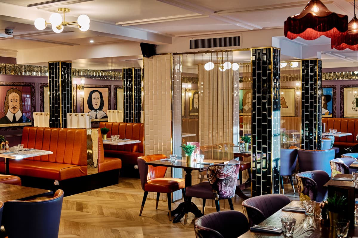 Restaurant interior at Hotel Cromwell with leather booths, eclectic chairs and portrait artwork.