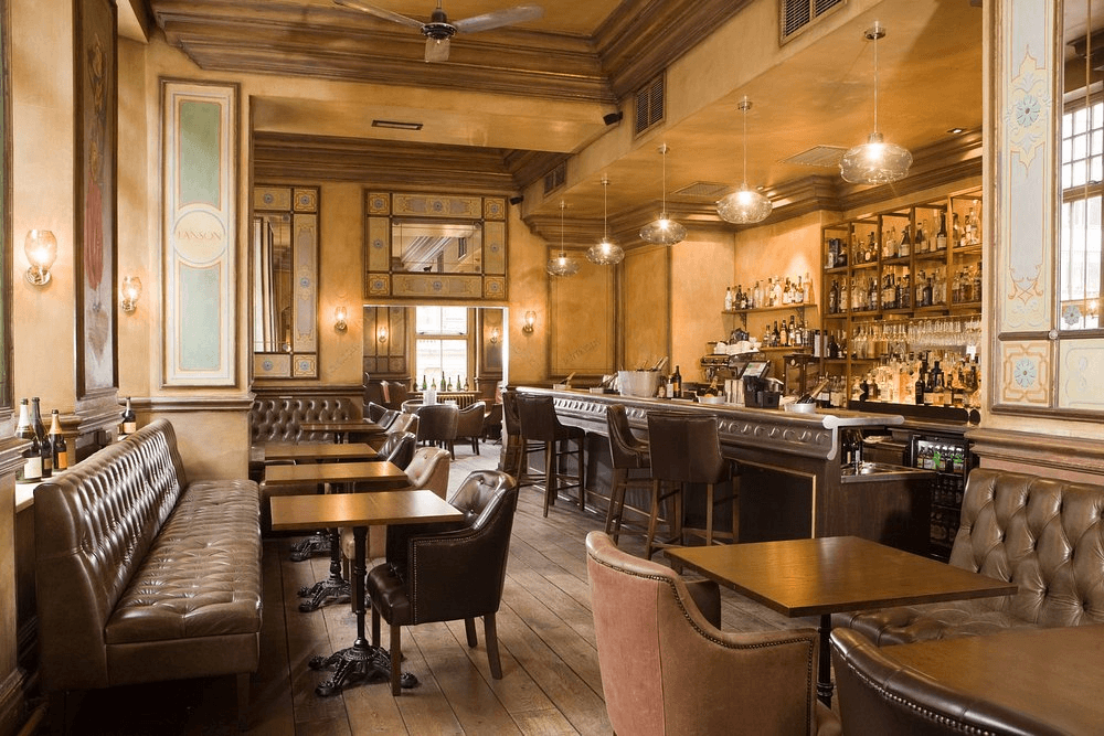 The bar interior at Hotel du Vin Birmingham with leather seating and bottle-lined shelves.
